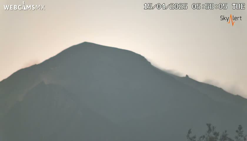 A hazy, overcast sky obscures a large, dark mountain in the distance.