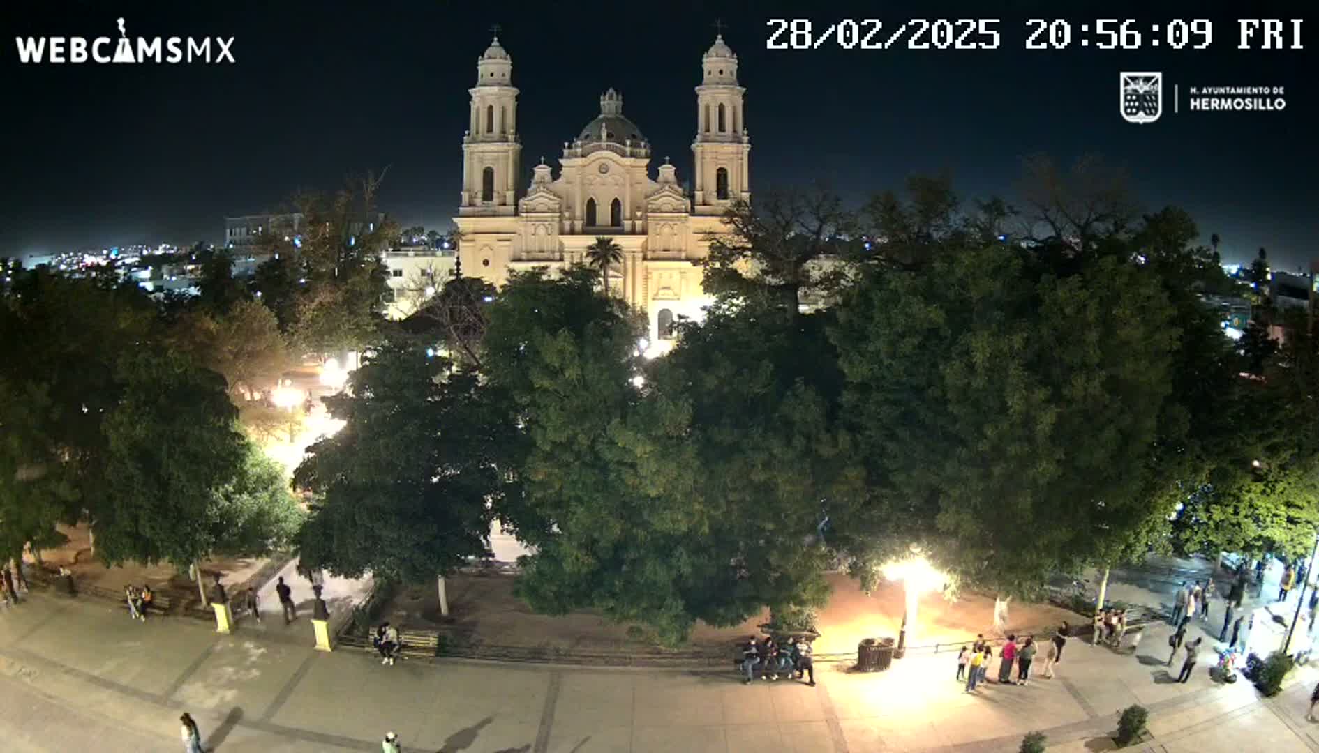 A nighttime view of a plaza with a large church in the background, under a clear sky.