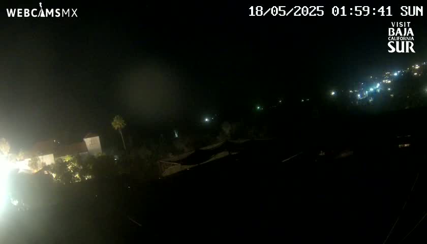 A nighttime, hazy view of a coastal town with a few lights visible in the distance.