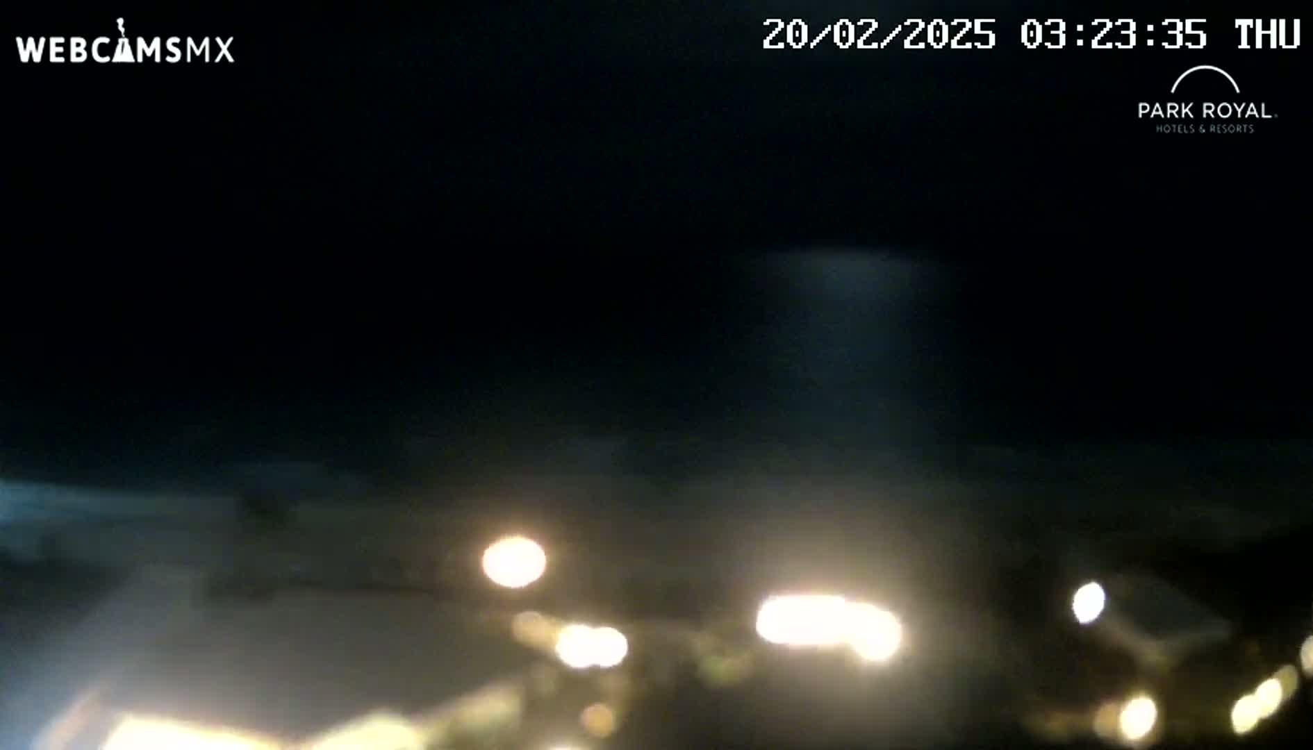 A nighttime outdoor scene shows blurry lights from vehicles in the bottom half of the frame against a dark sky.