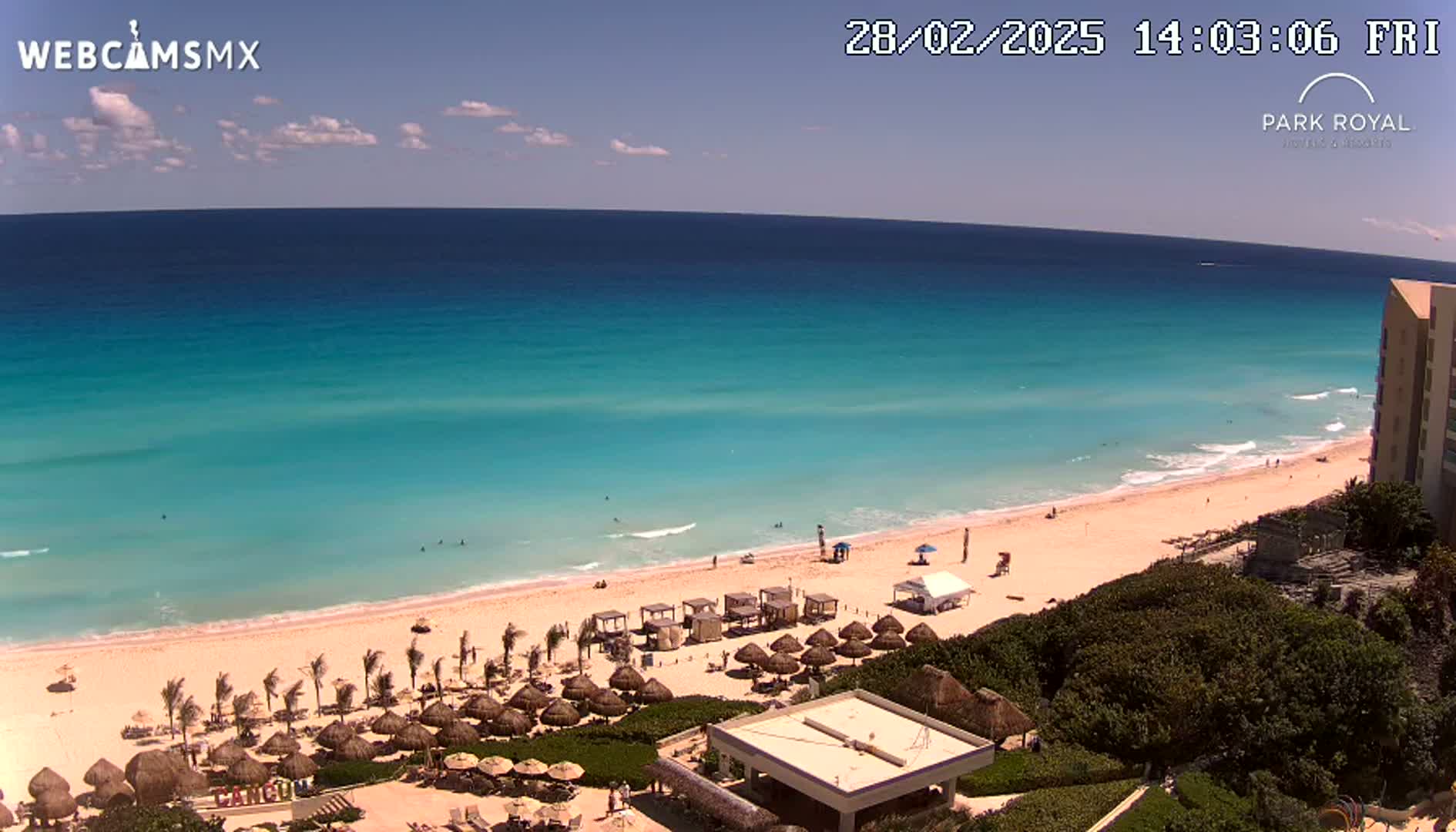 A beach with turquoise water and many thatched umbrellas under a clear, sunny sky.