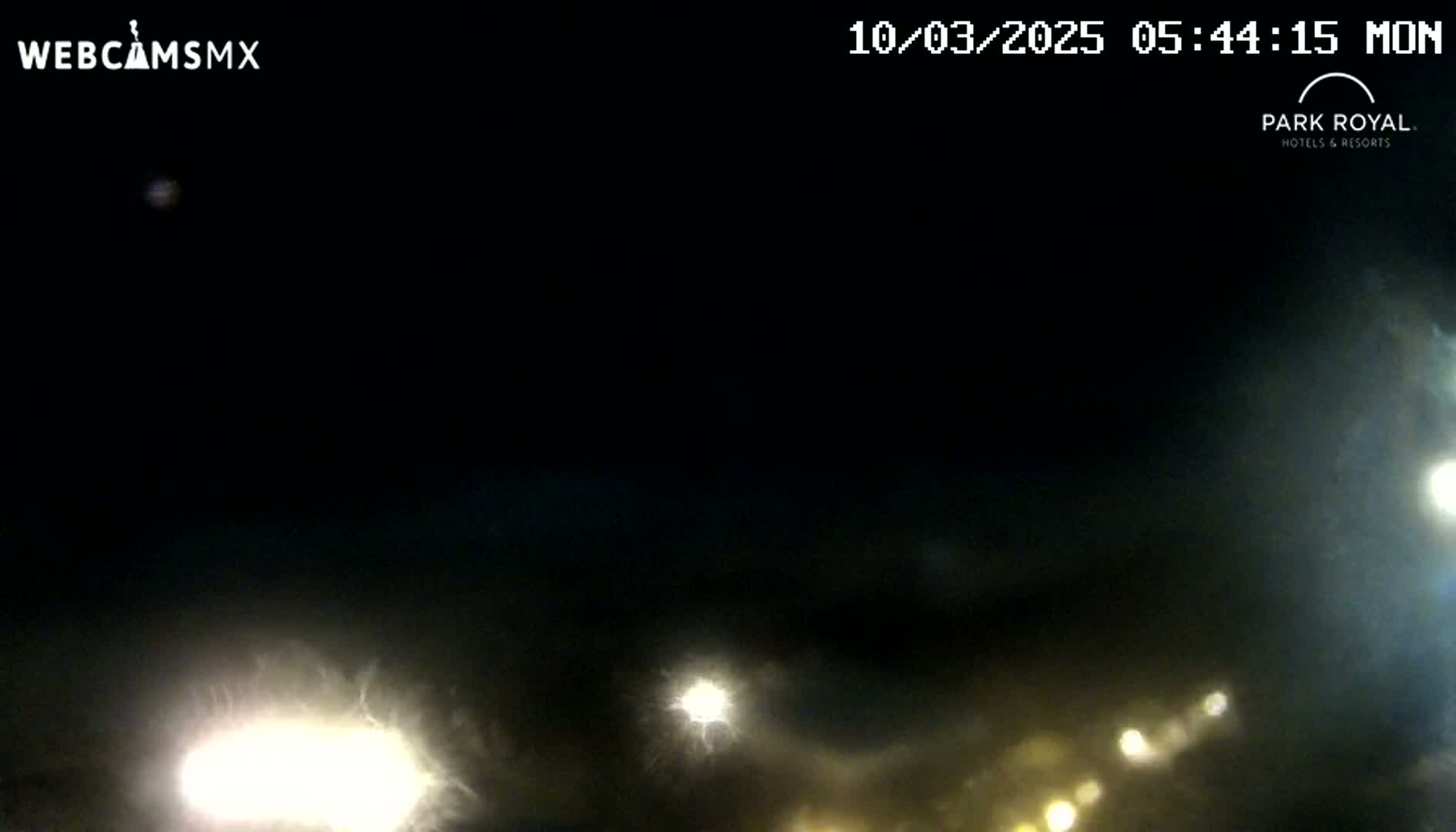 A nighttime, cloudy scene shows the headlights of distant vehicles.