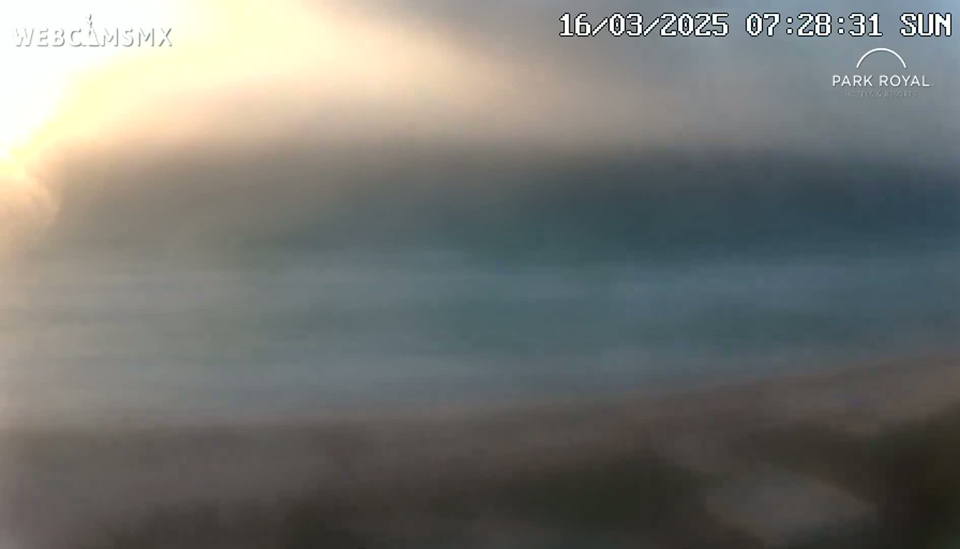 A hazy sunrise over a calm body of water.