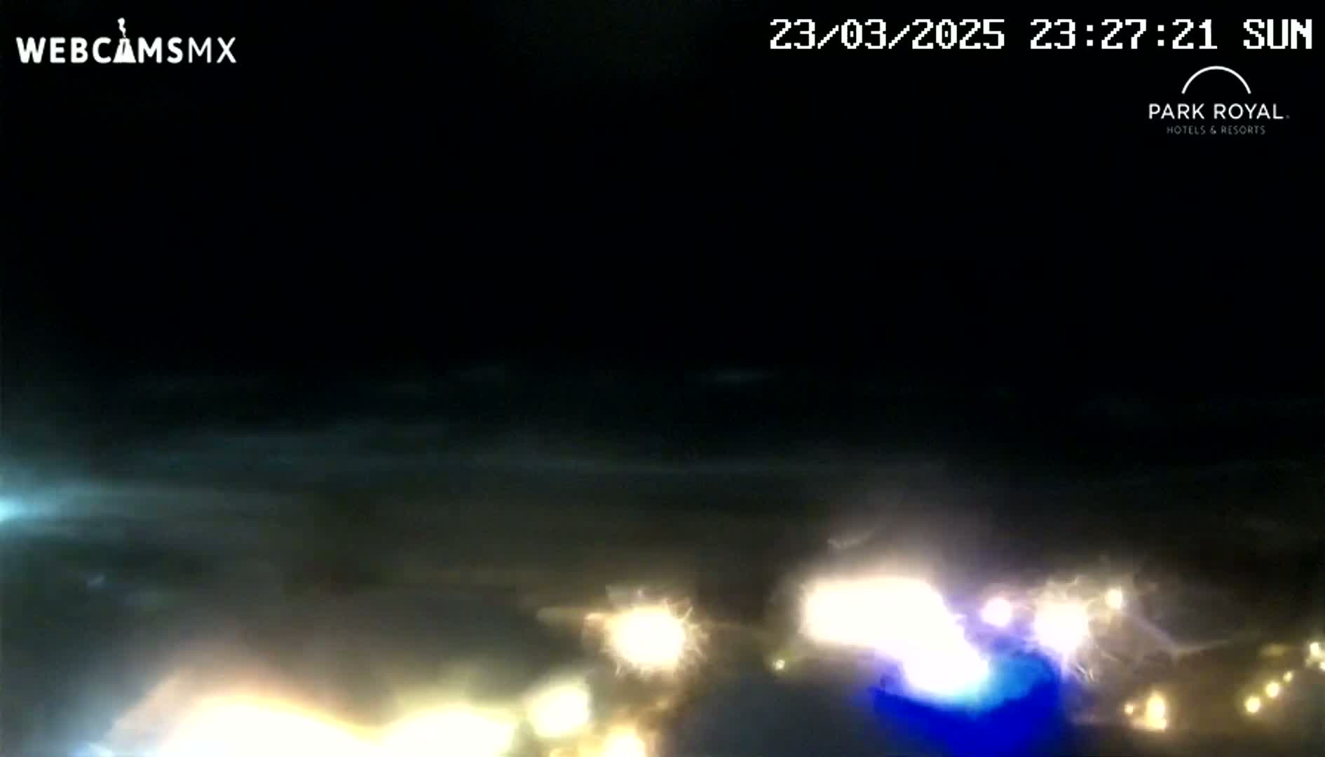 At night, under a dark sky, blurry lights from vehicles are visible in the distance.