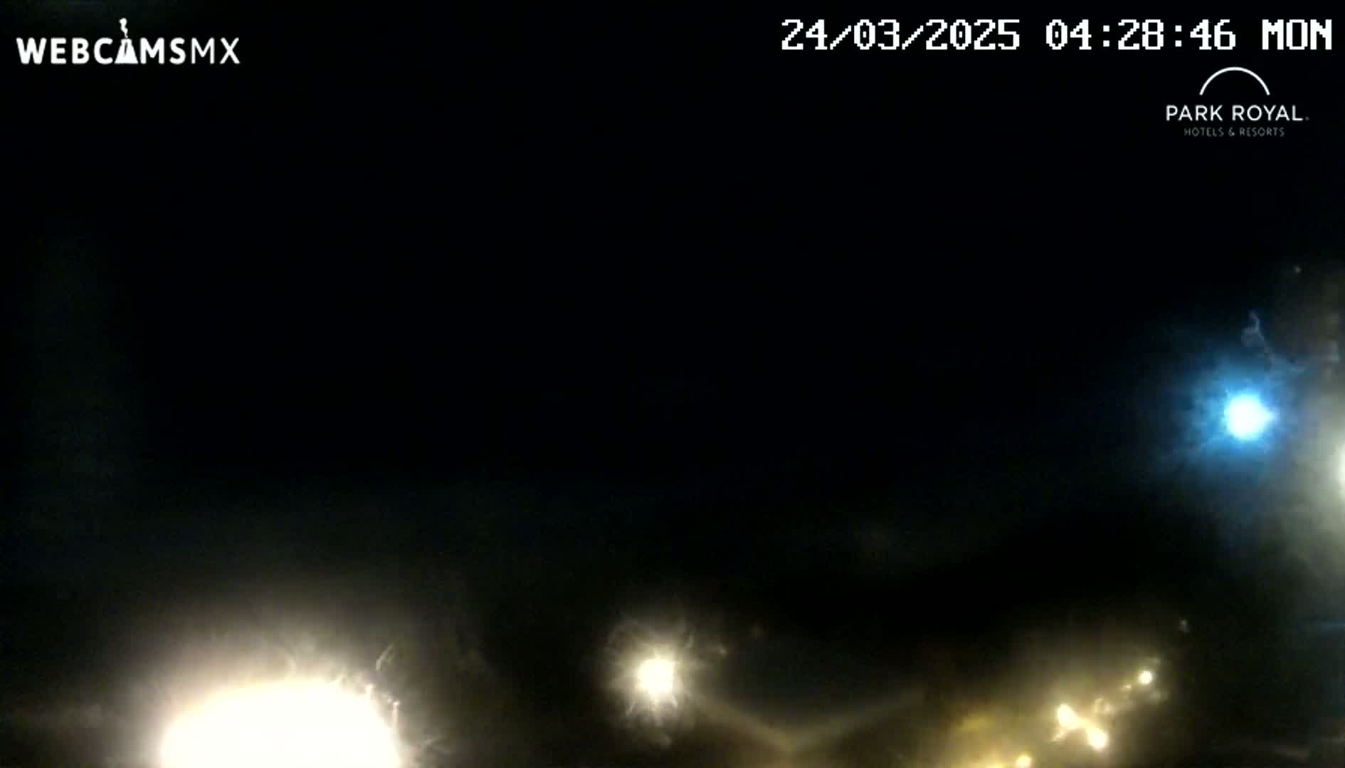 At night, several bright lights are visible in the distance, with a mostly dark sky above.
