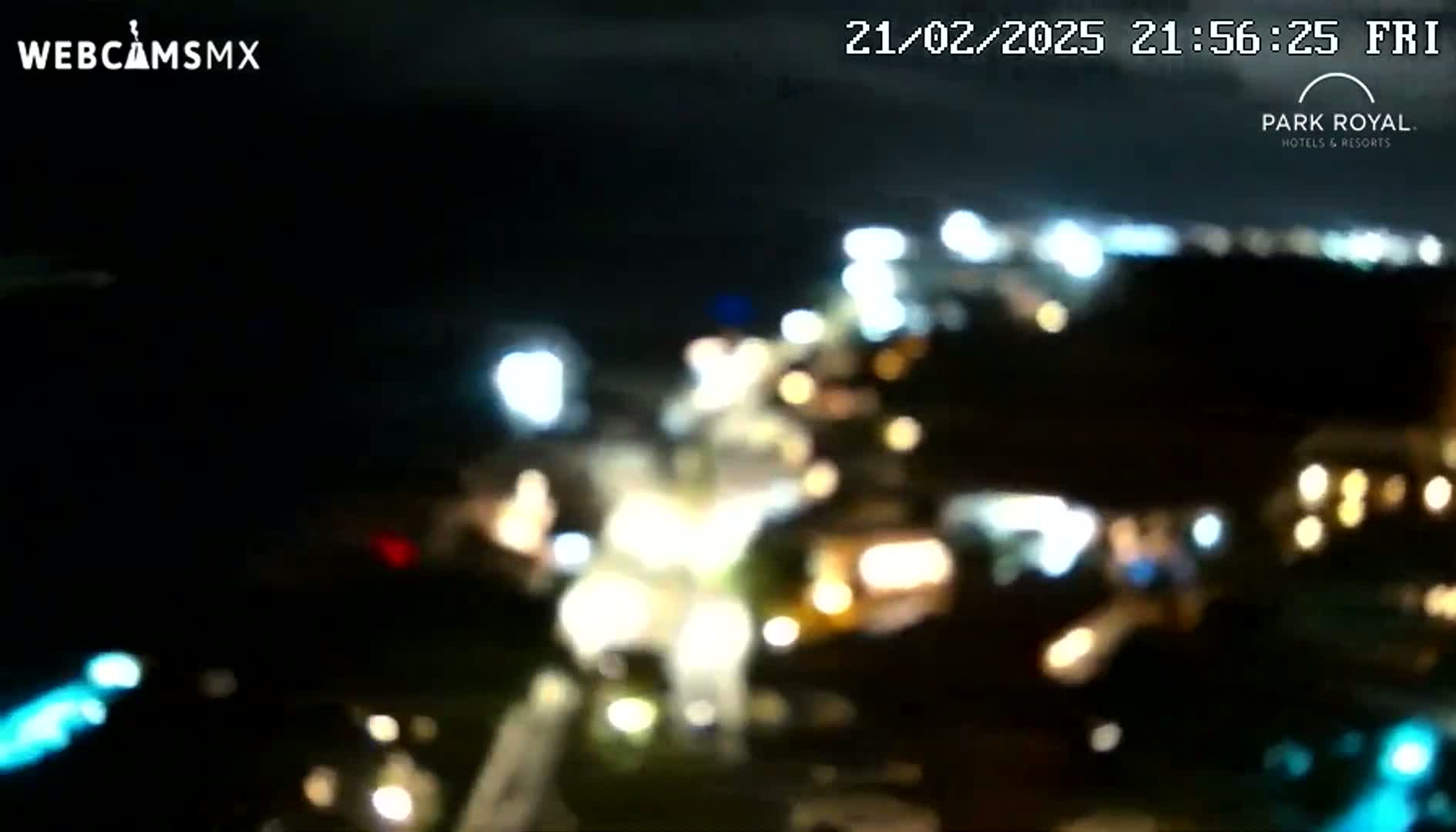 A blurry nighttime image shows a collection of out-of-focus lights from what appears to be a resort or town.