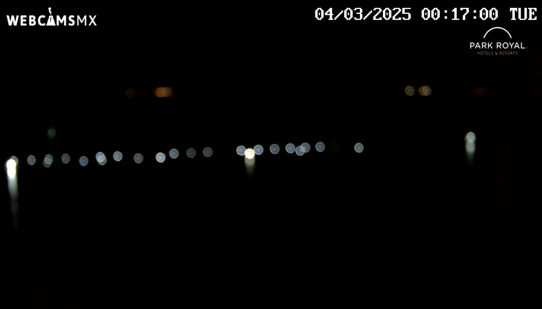 A nighttime, dark scene shows a blurry line of lights in the distance.