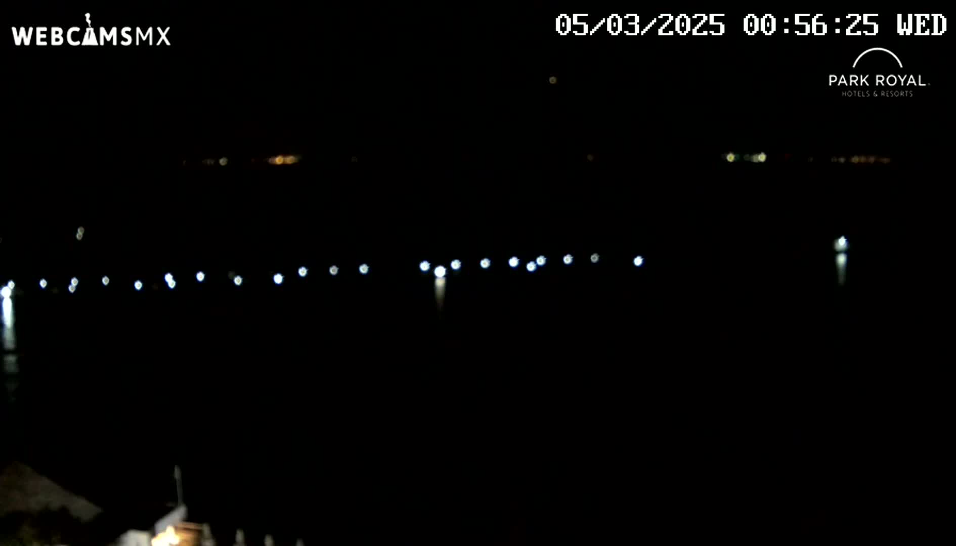 At night, a body of dark water reflects a line of distant lights.