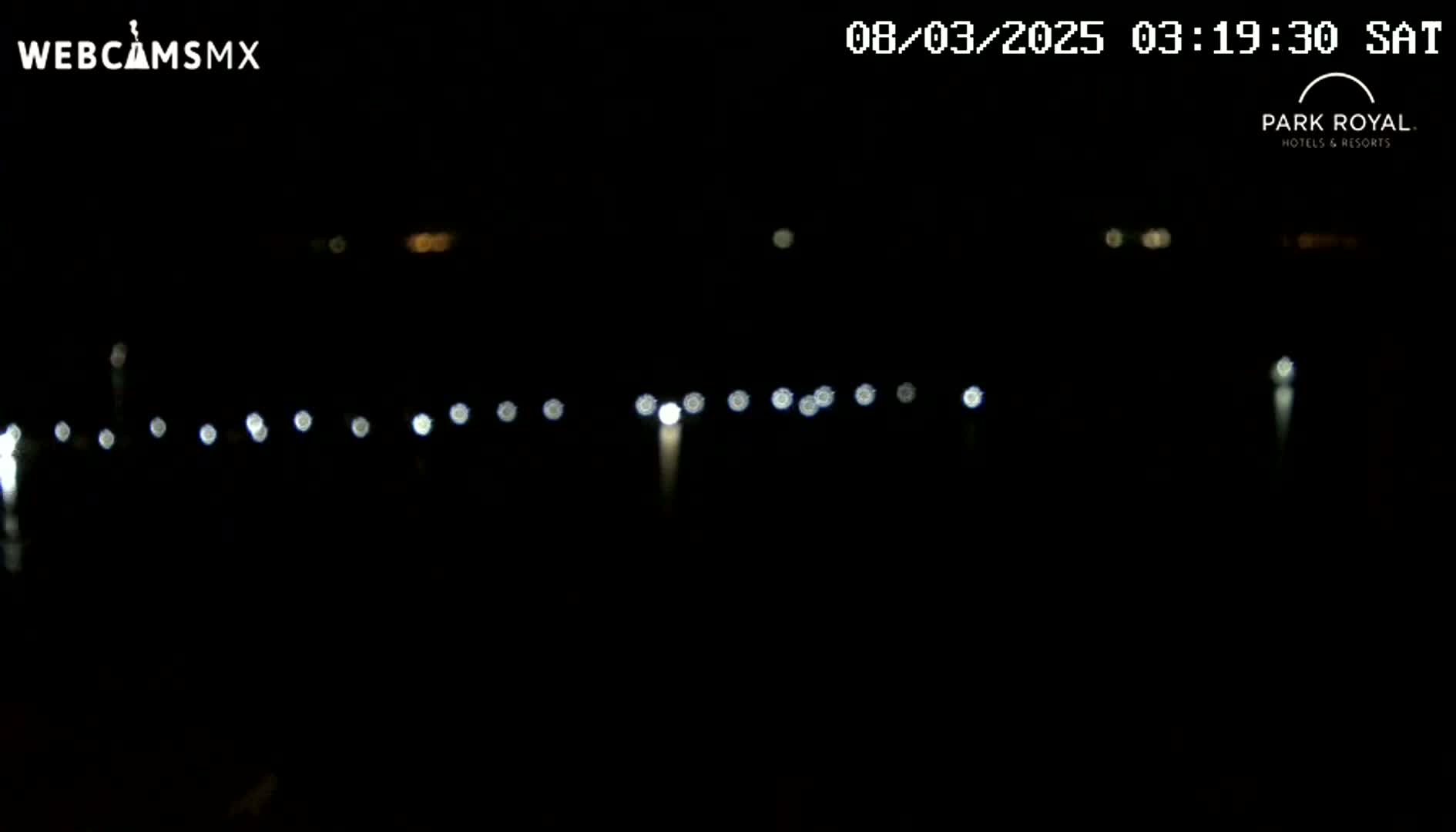 A dark nighttime scene shows a blurred line of lights in the distance.