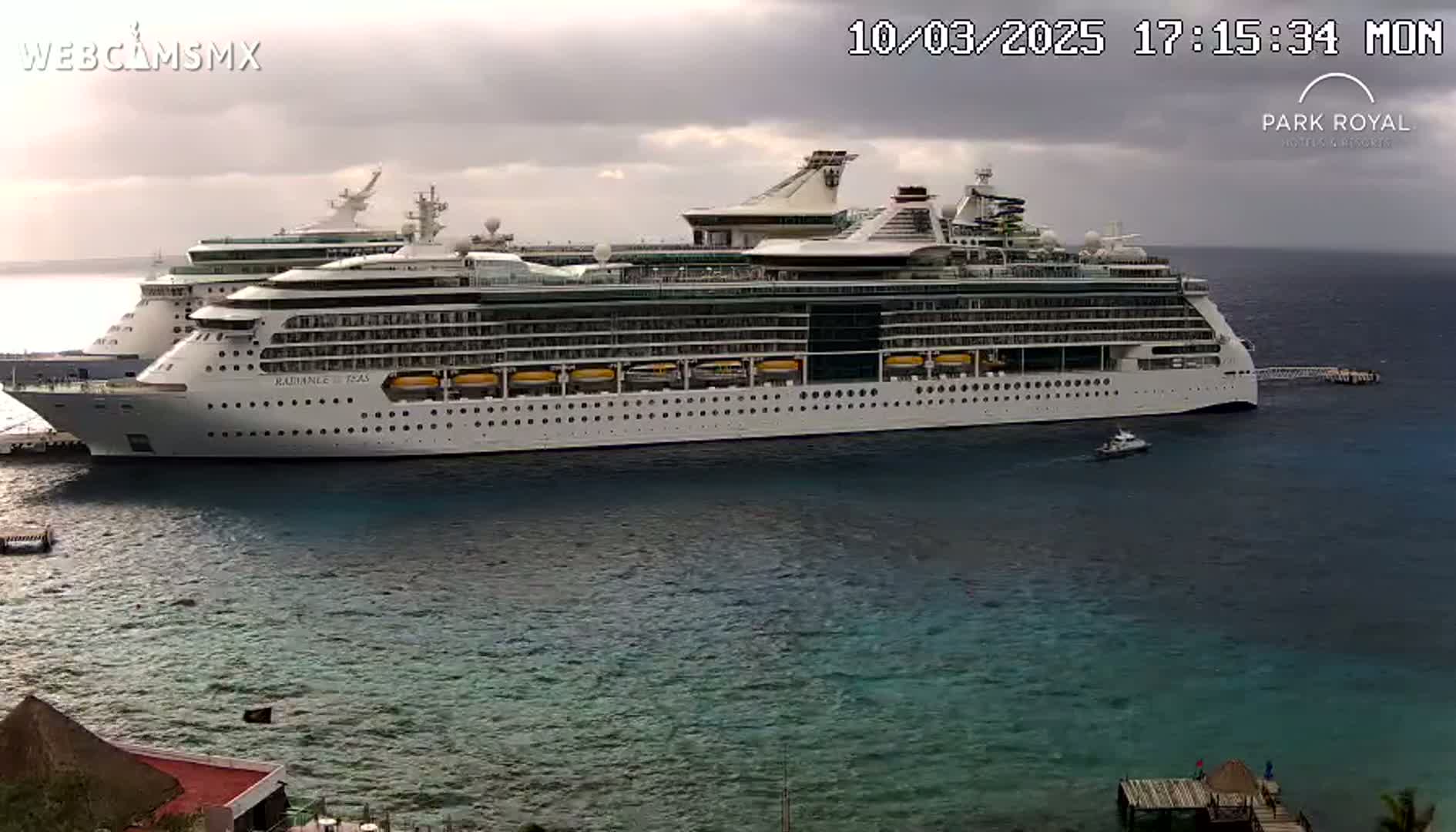 A large cruise ship is docked at a pier on a partly cloudy day.