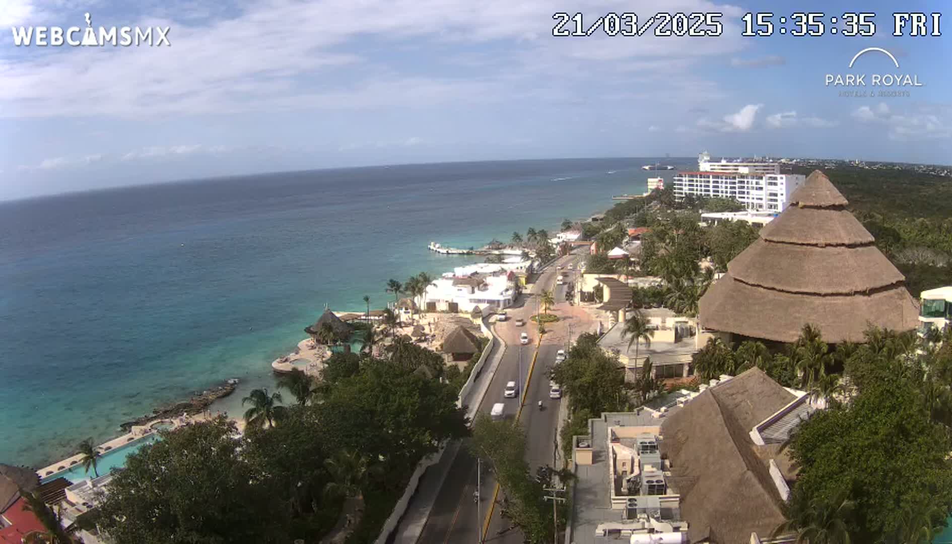 An aerial view shows a resort town on a clear, sunny day next to a calm, turquoise ocean.