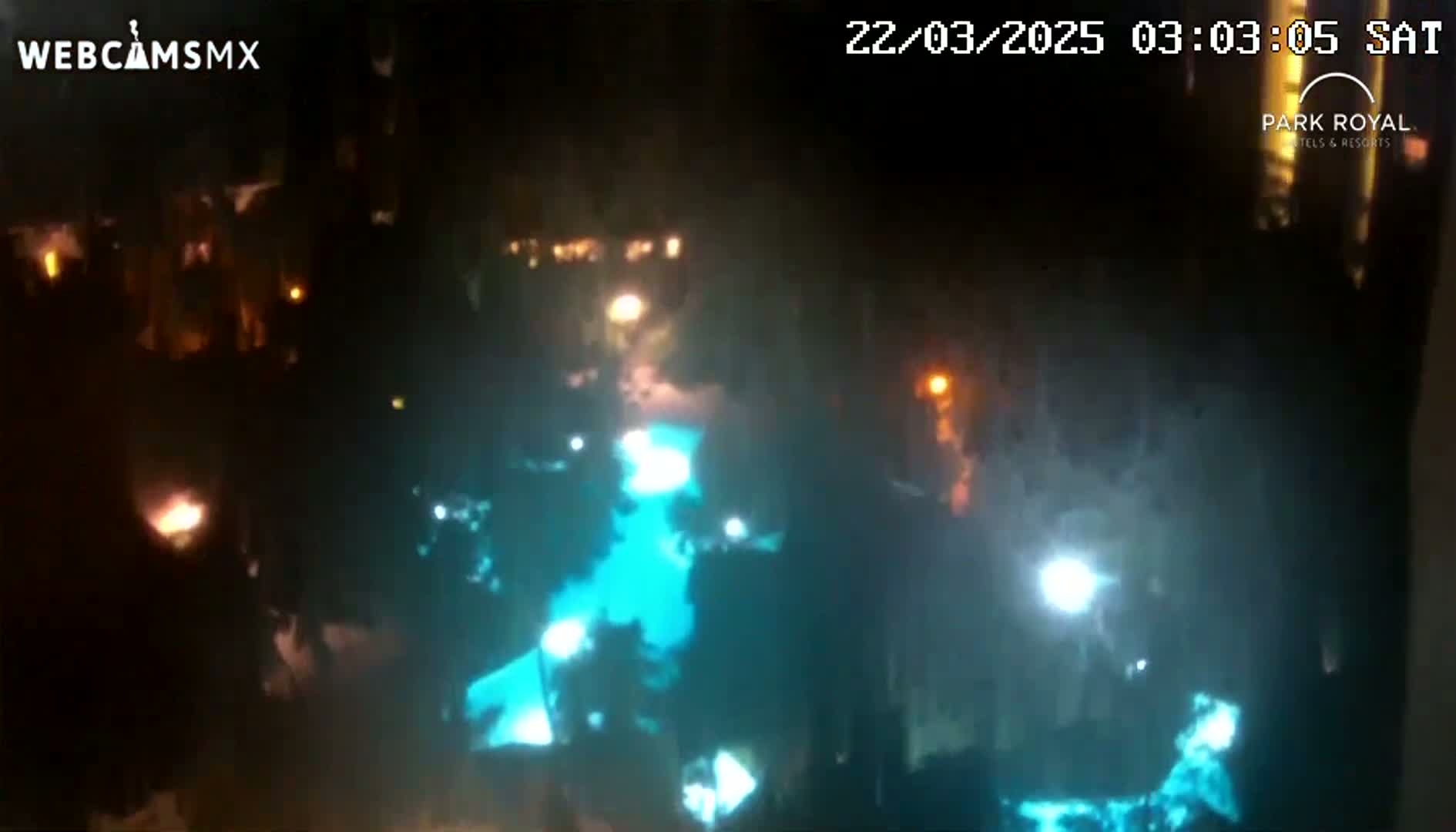 A nighttime, overhead view shows a teal-lit pool surrounded by dark buildings and sparsely lit areas.