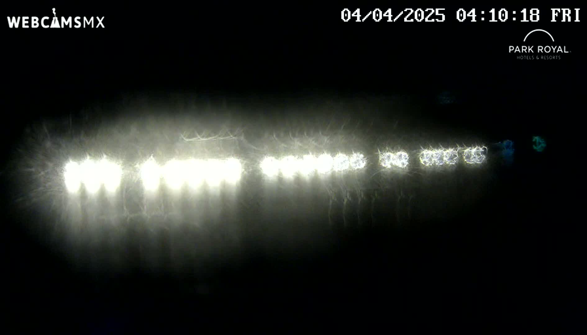 A nighttime, hazy scene shows a line of bright headlights in the distance.