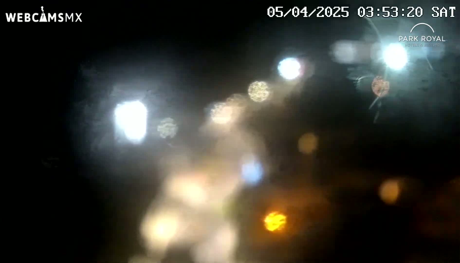 Blurred out-of-focus lights are visible through a rain-streaked window at night.