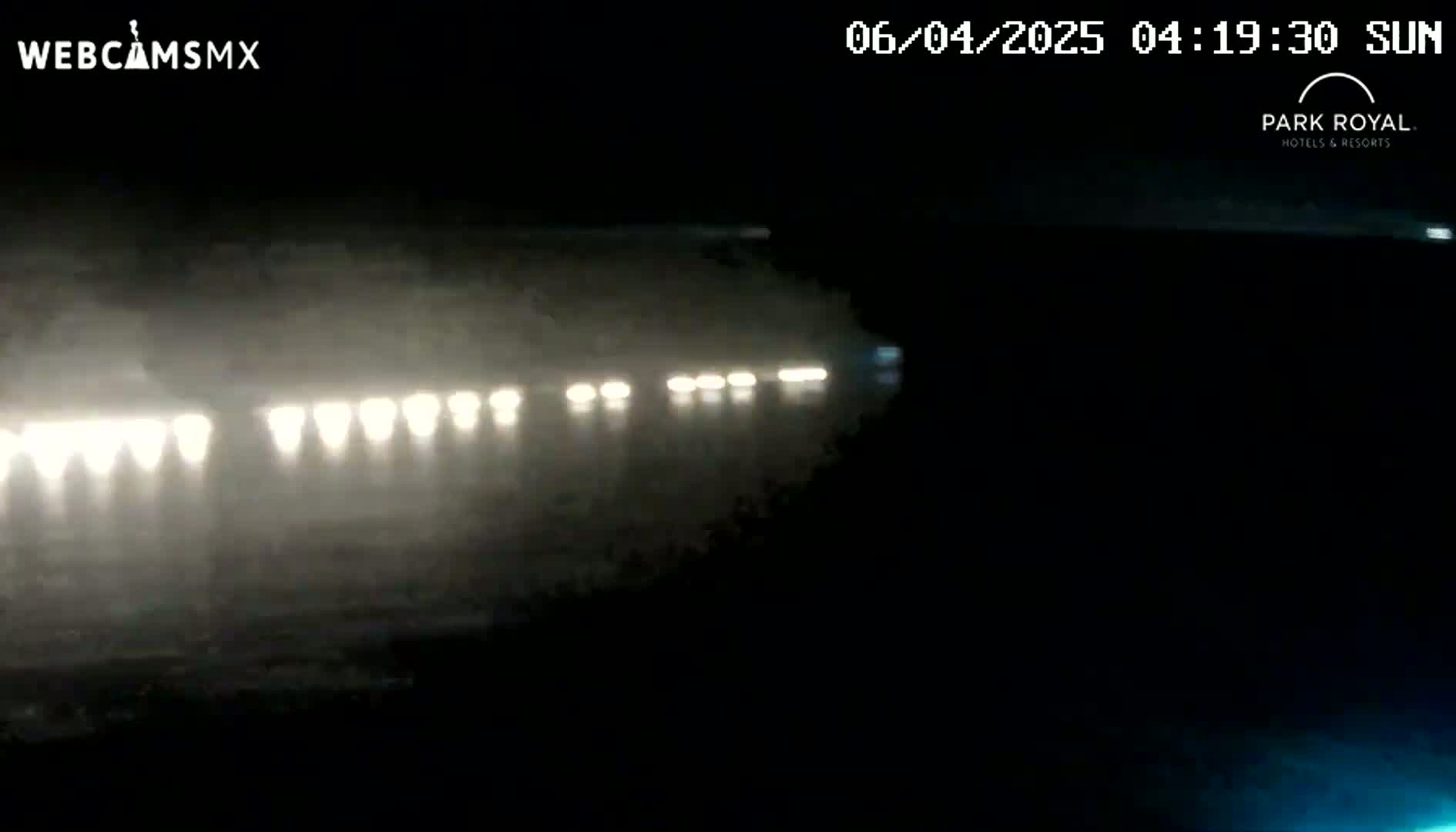 A nighttime, blurry view of a row of headlights in foggy or misty conditions.