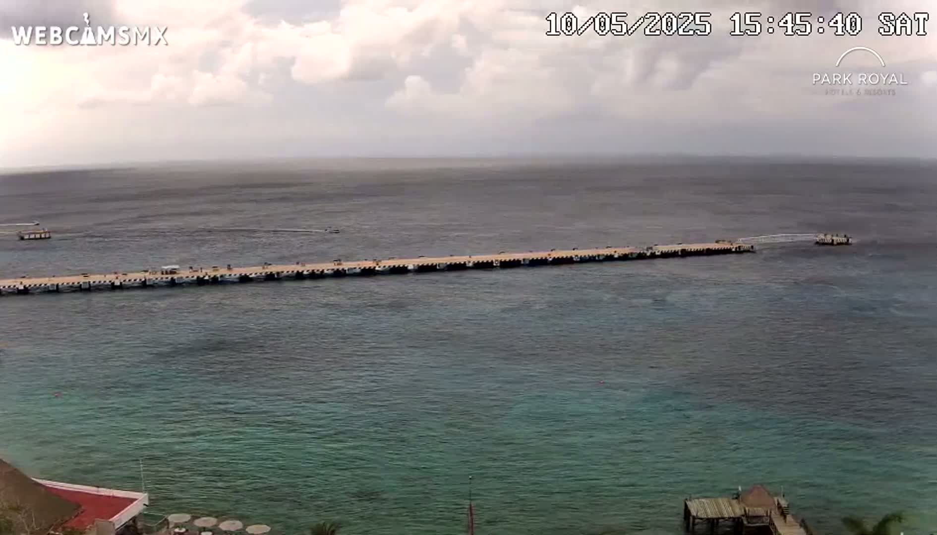 A long pier extends into a calm, somewhat overcast ocean.