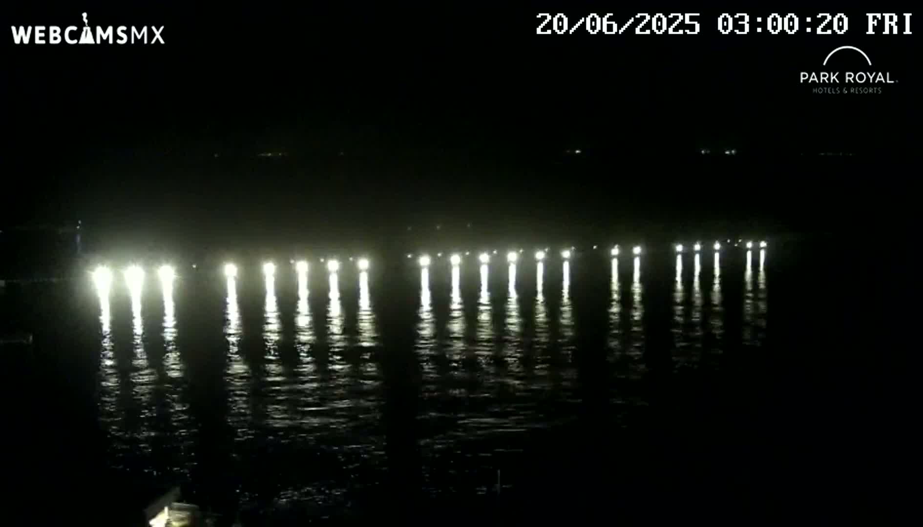 At night, a series of bright lights are reflected on dark water.