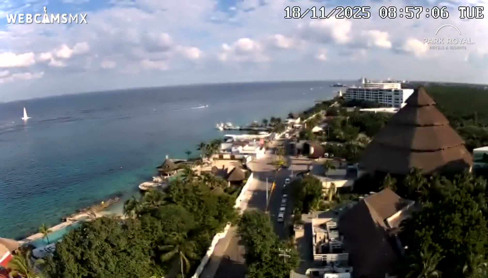 A clear, dark night reveals a long row of illuminated lights stretching across calm water, with their reflections prominent below and a distinct red light visible on the right.