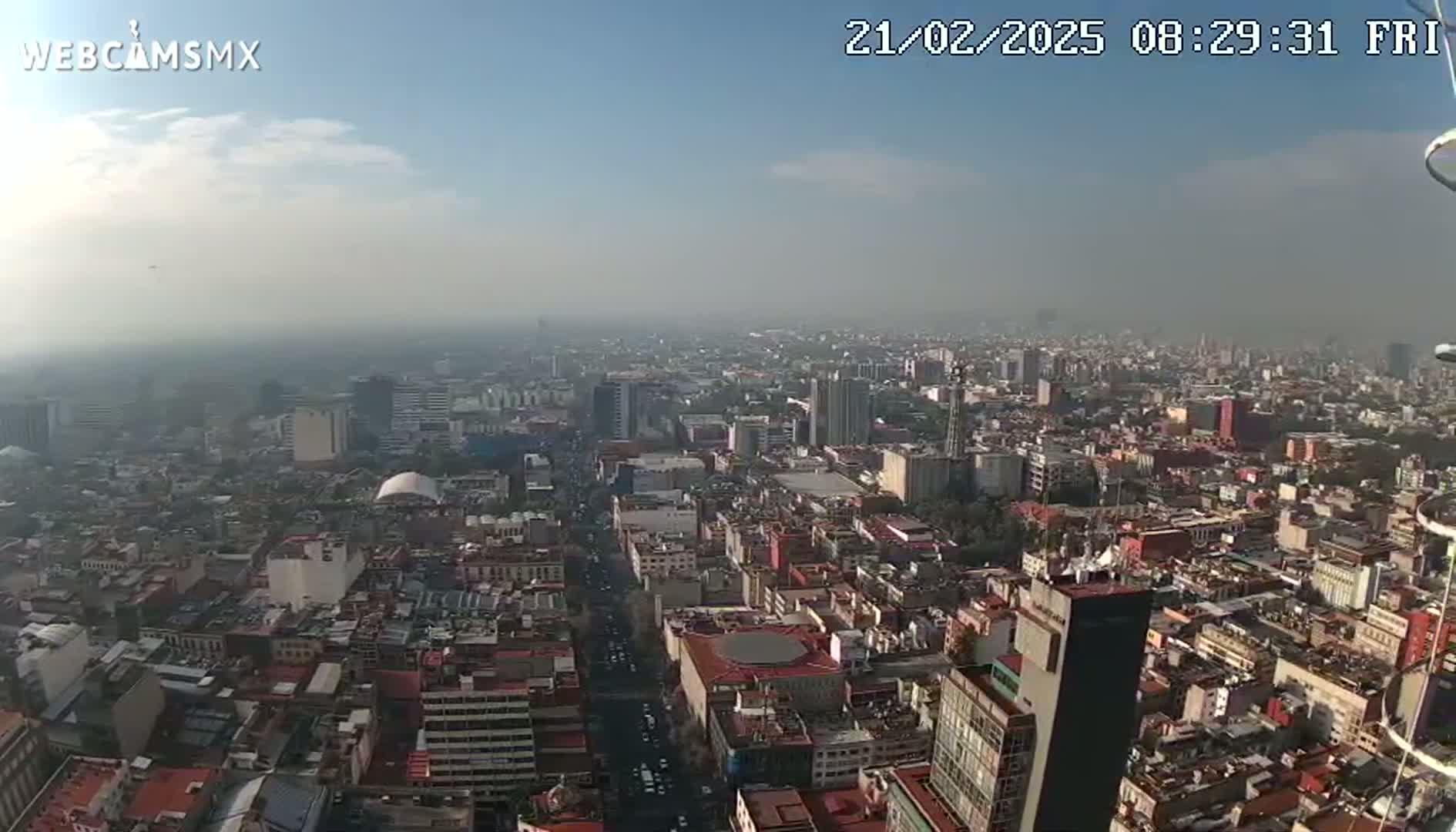 A hazy, sunny day reveals a sprawling cityscape viewed from a high vantage point.