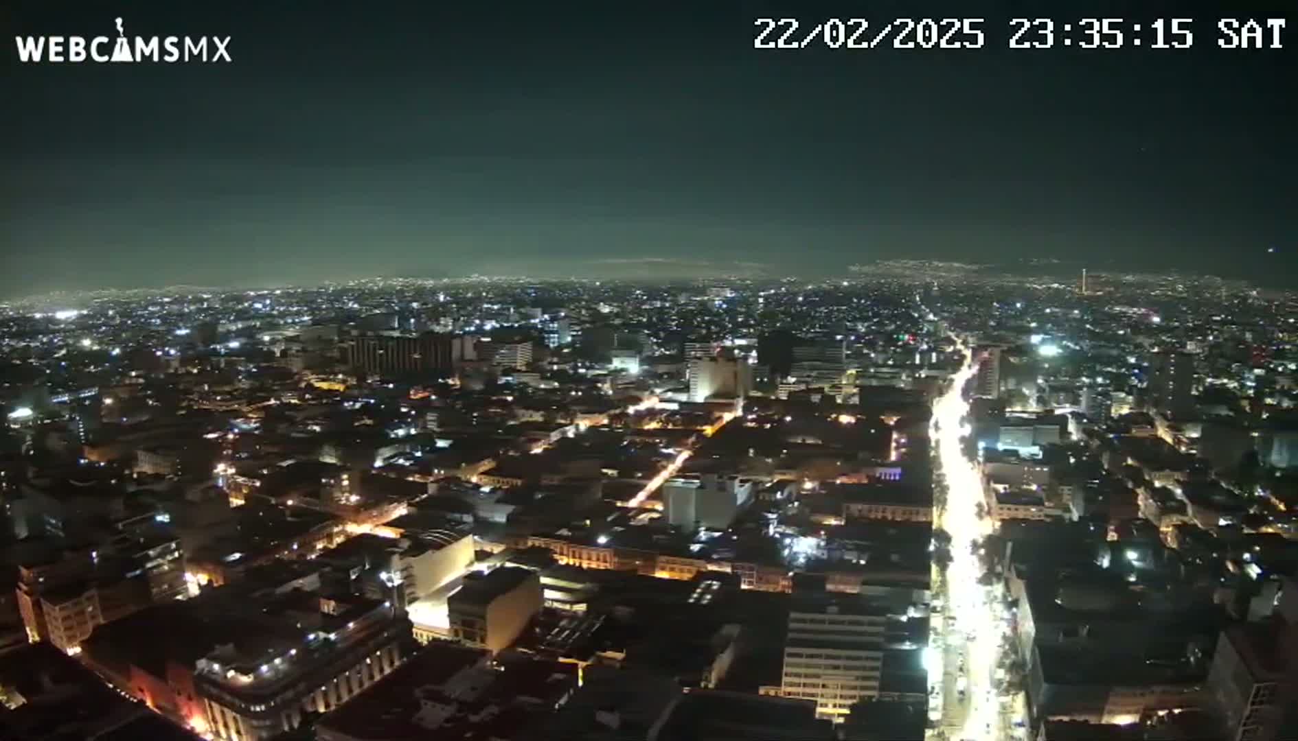 A nighttime aerial view of a city with brightly lit streets and buildings under a clear sky.
