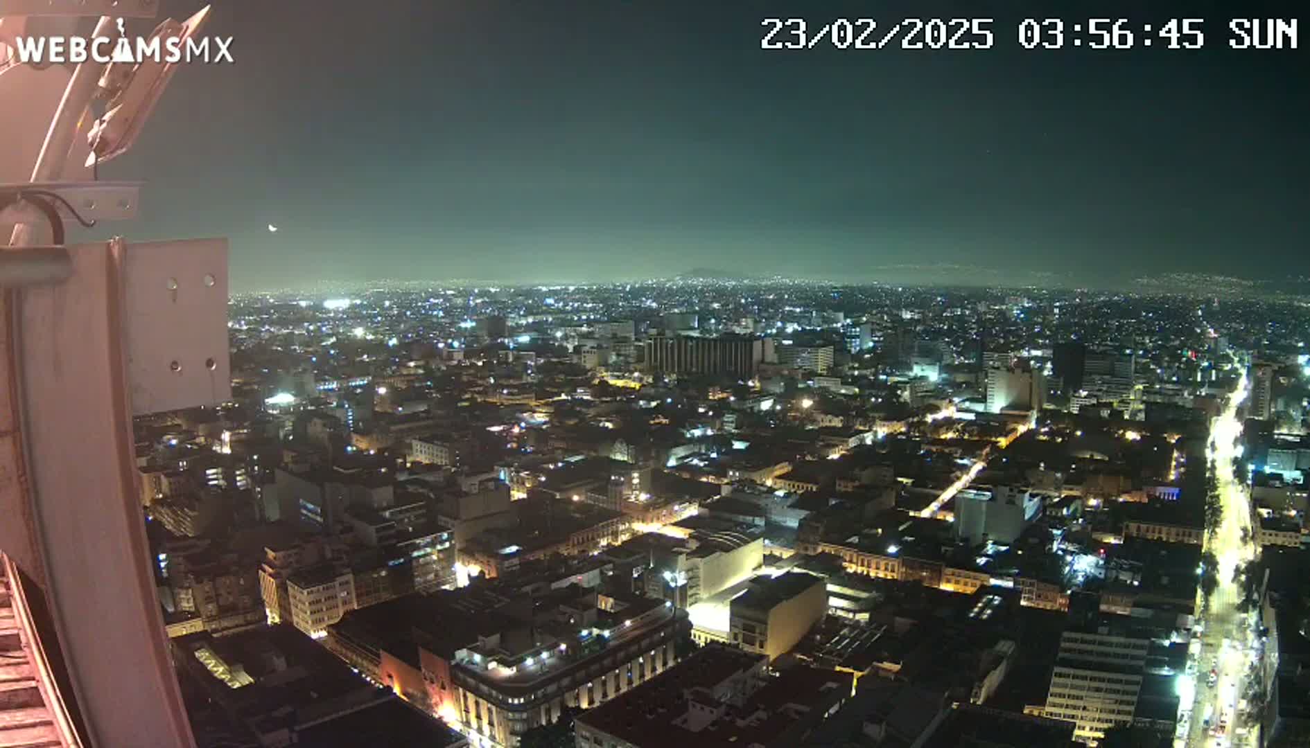 A nighttime aerial view of a sprawling city illuminated by countless lights under a clear, dark sky.