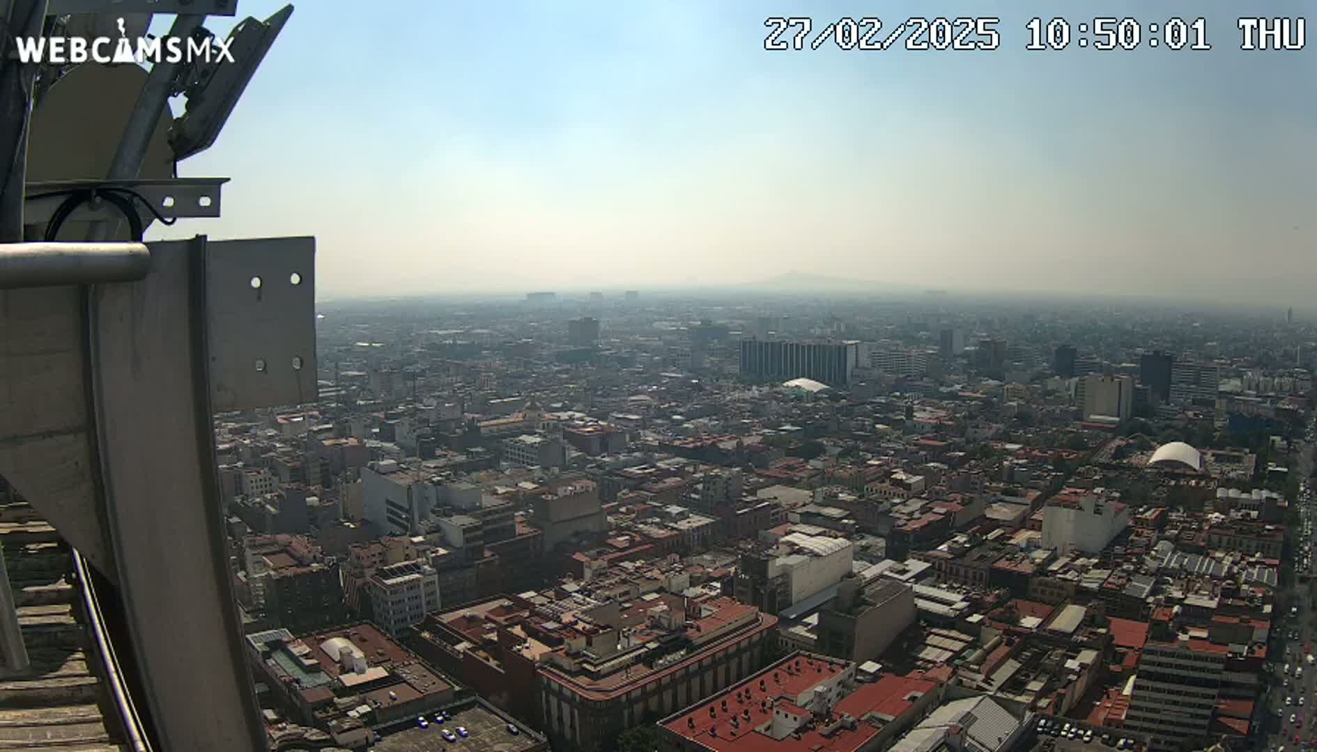 A hazy, sunny view from a tall structure overlooking a dense cityscape.