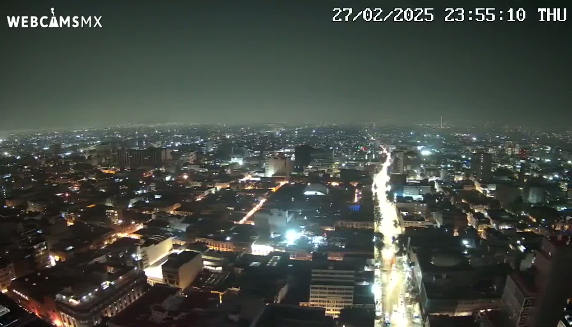 A nighttime, hazy view of a sprawling city with illuminated streets and buildings.