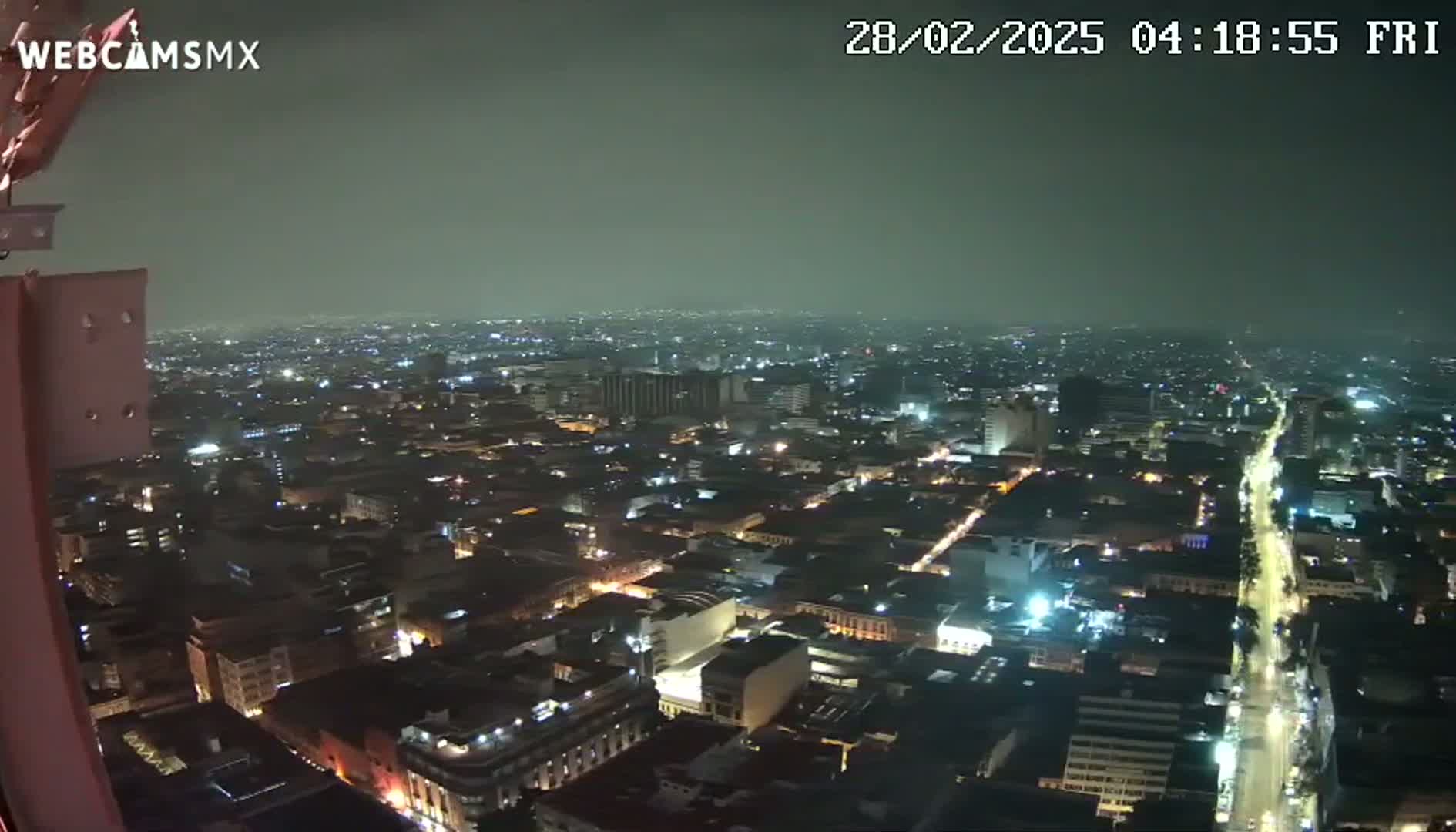 A nighttime, hazy view of a sprawling city with brightly lit streets and buildings.