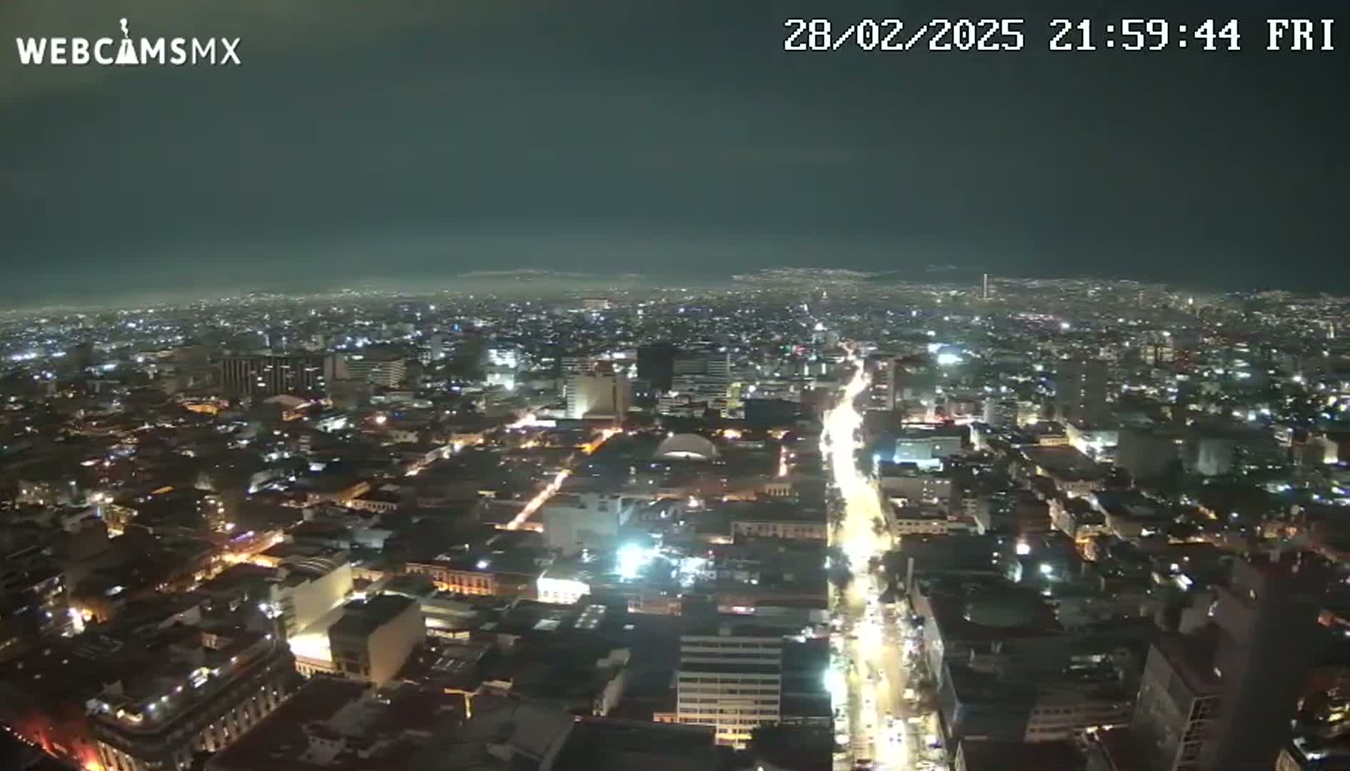 A nighttime aerial view of a brightly lit city under a dark, clear sky.