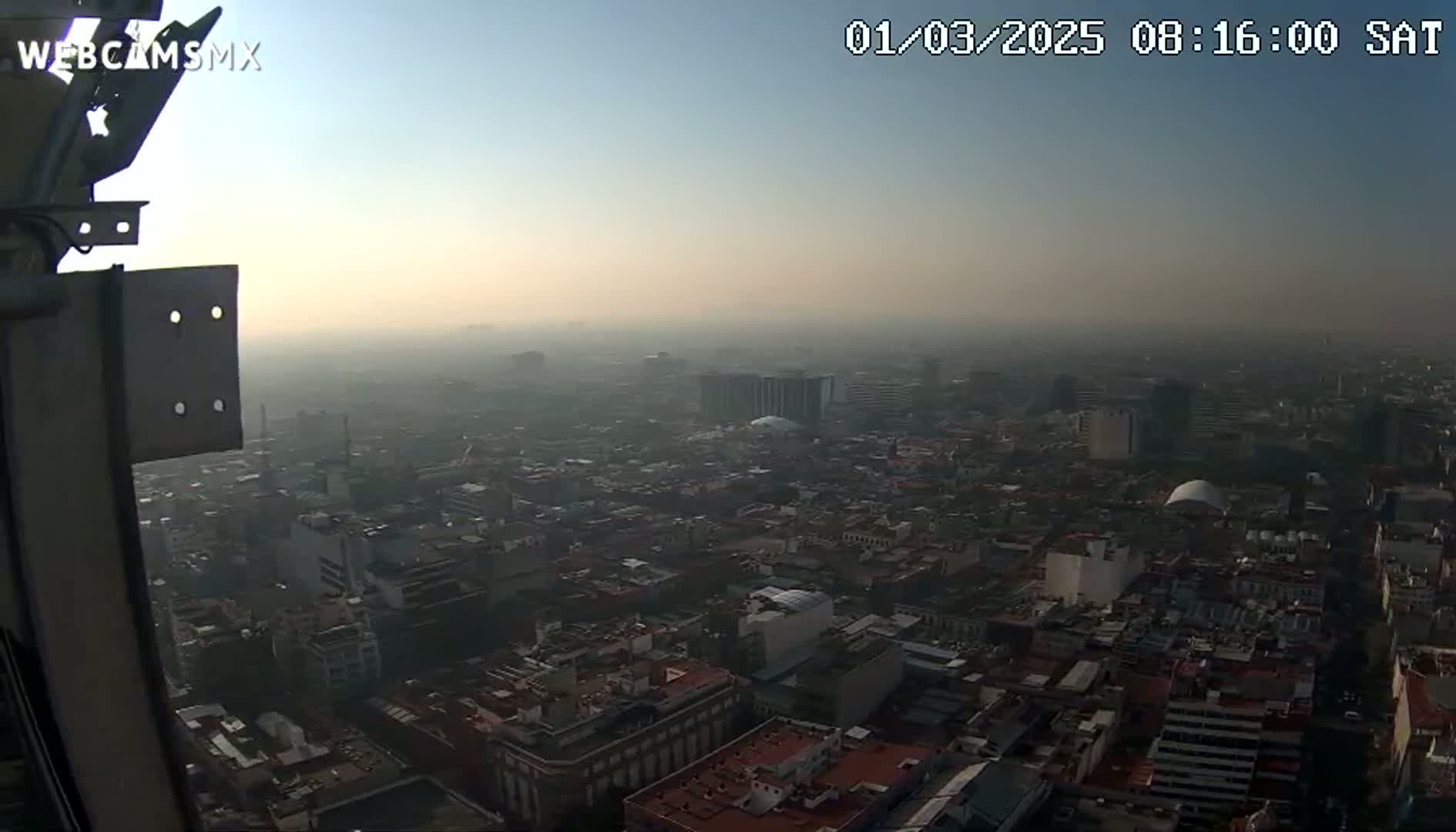 A hazy, sunrise view from a tall structure overlooks a sprawling city.
