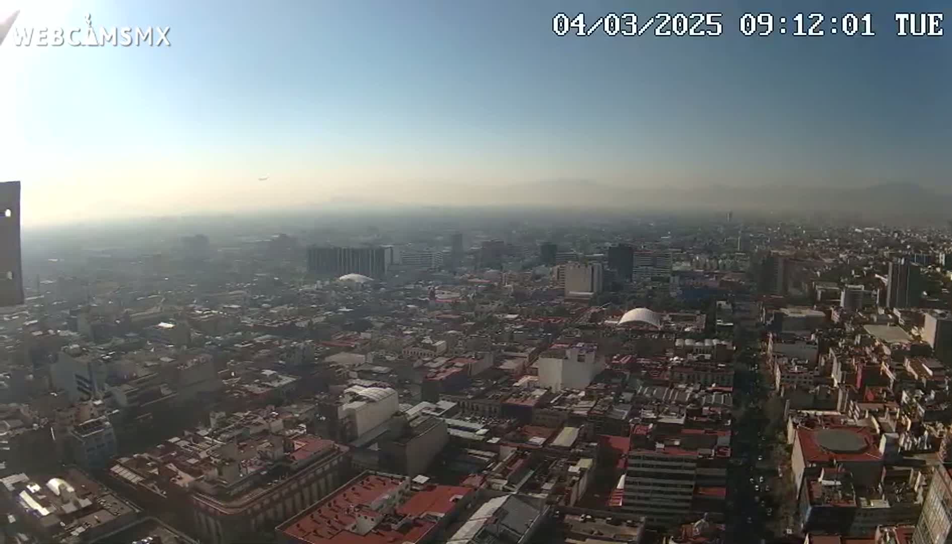 A hazy, sunny aerial view of a dense city with many low-rise buildings.