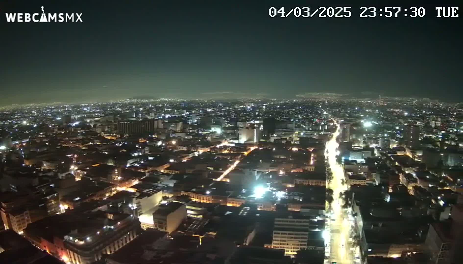 A nighttime, high-angle view of a sprawling city illuminated by streetlights and building lights.