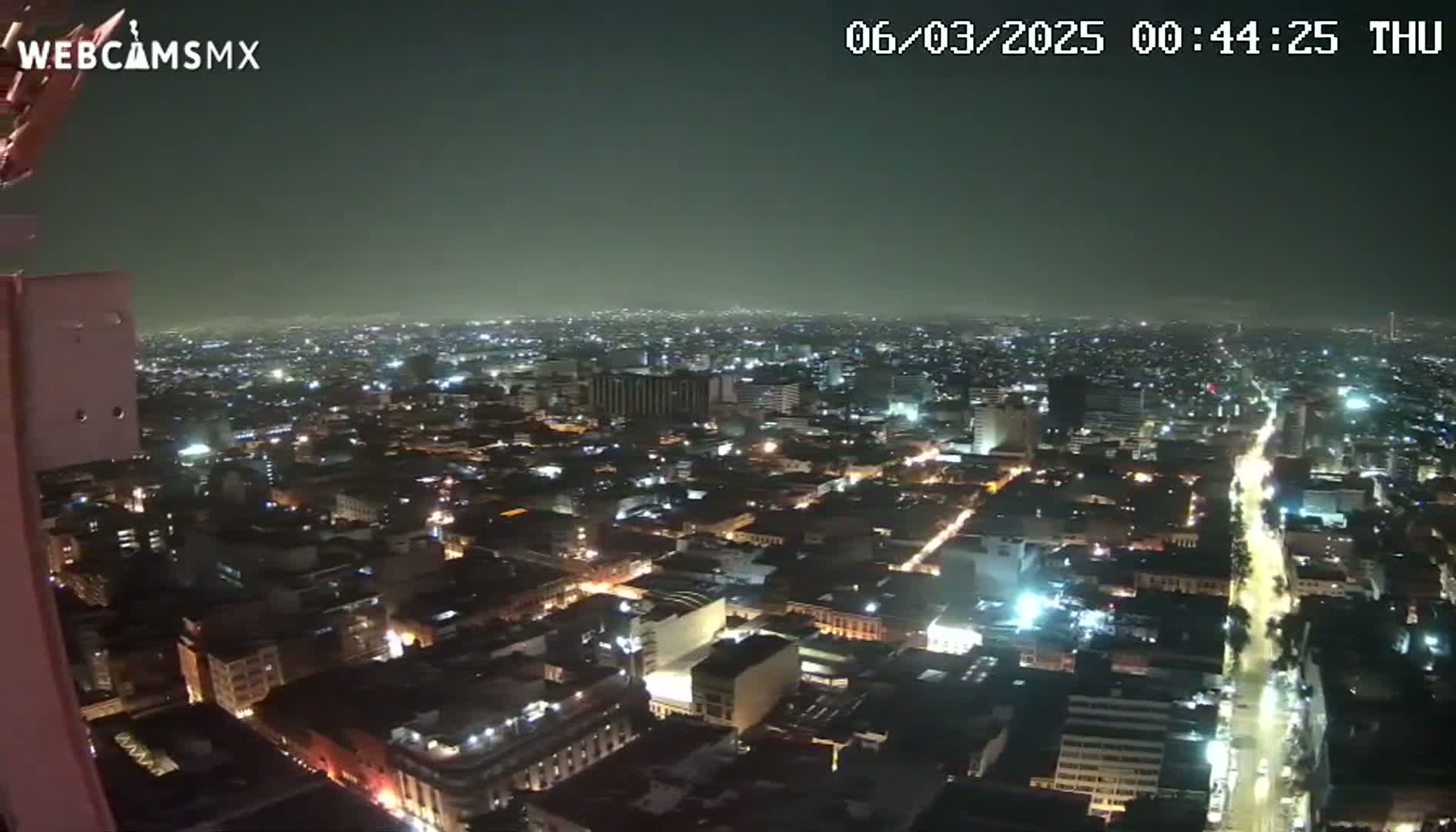 A nighttime, high-angle view of a sprawling city with numerous illuminated buildings and streets.