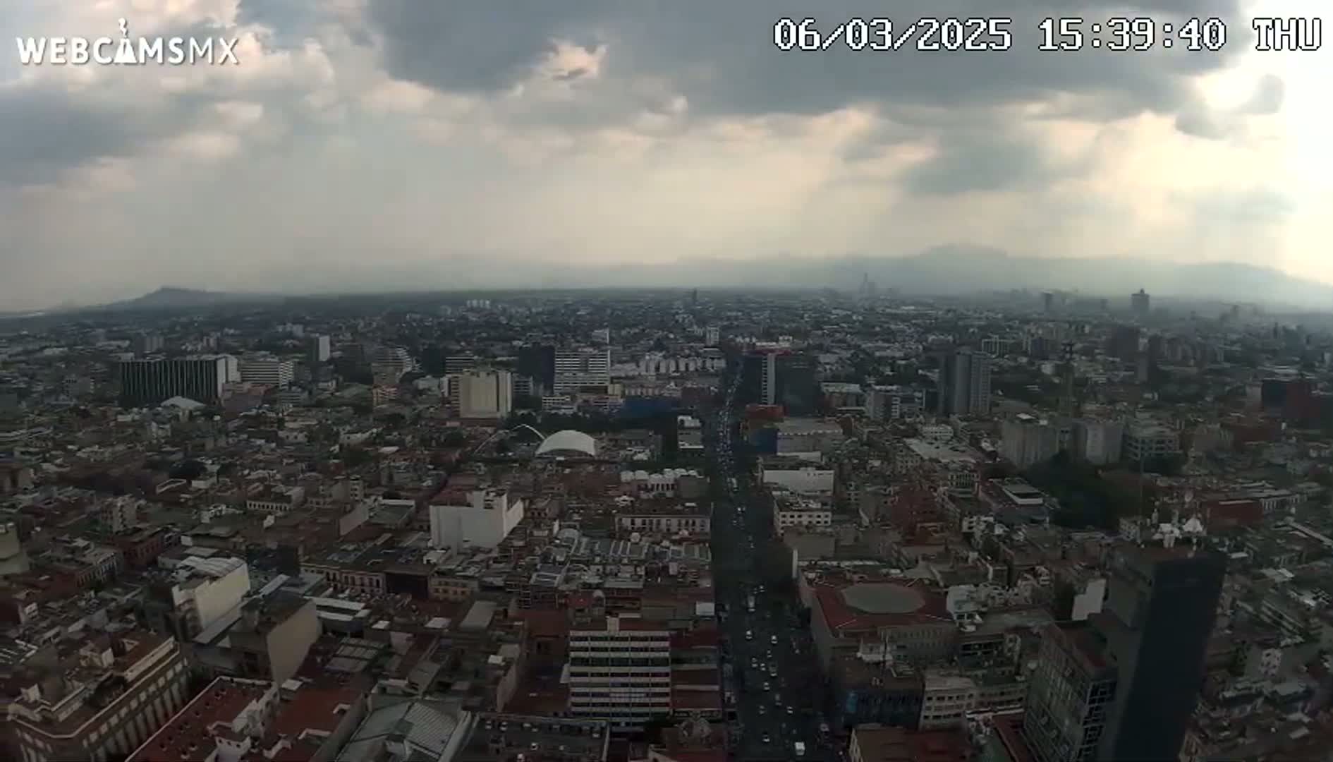 A sprawling city, under a cloudy sky, is viewed from a high vantage point.