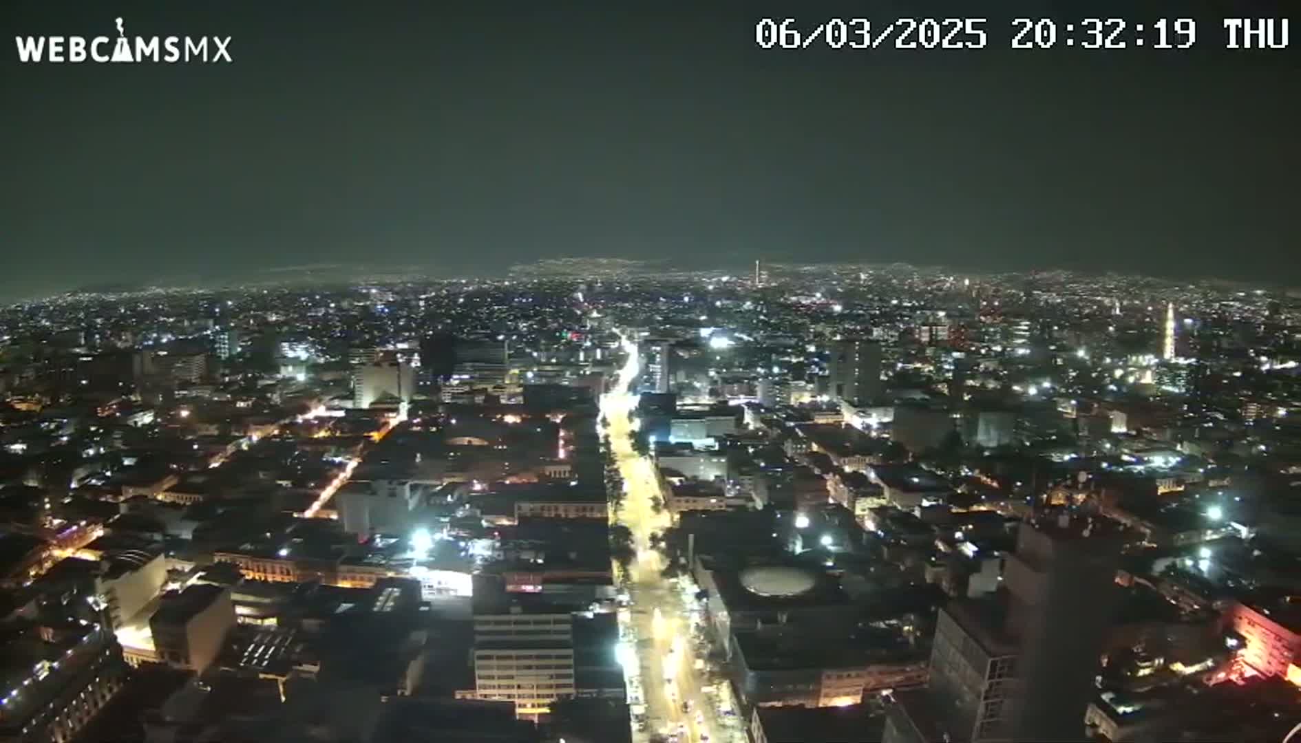 A nighttime, high-angle view of a sprawling city illuminated by streetlights and building lights.
