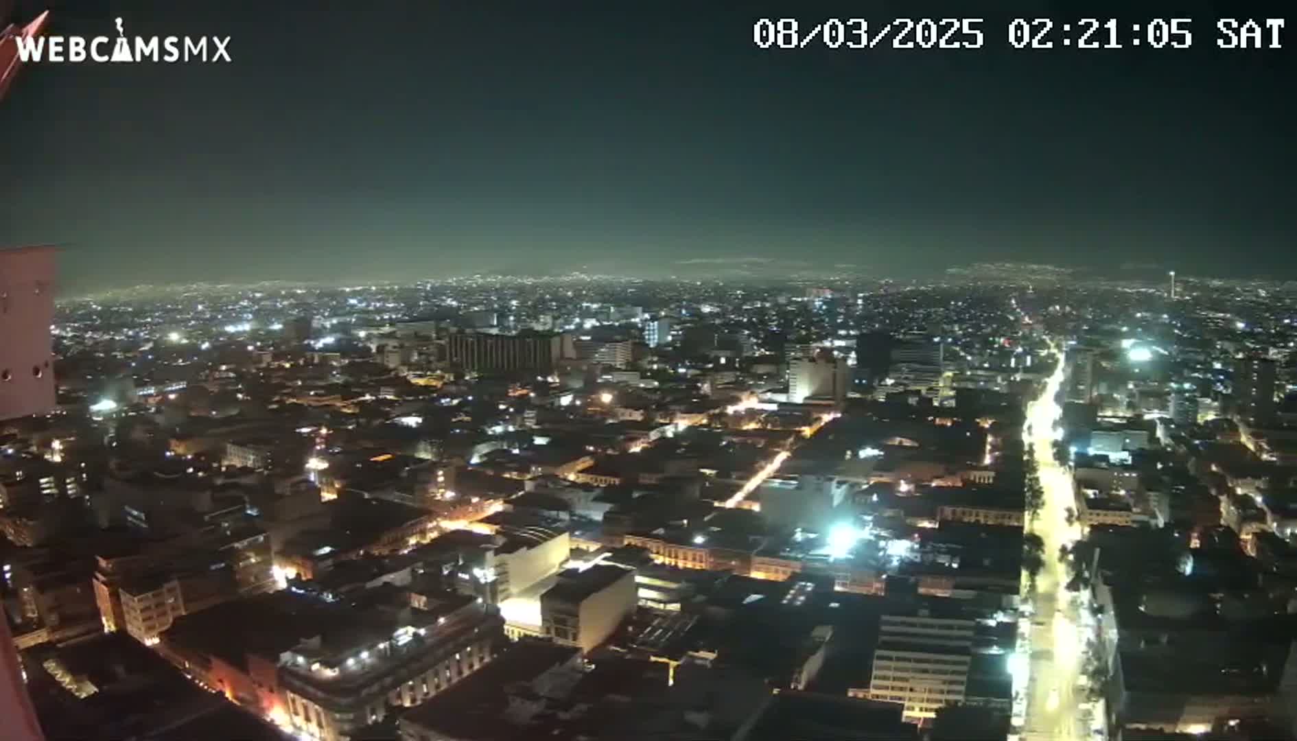 A nighttime, high-angle view shows a sprawling city illuminated by numerous streetlights and building lights under a clear, dark sky.
