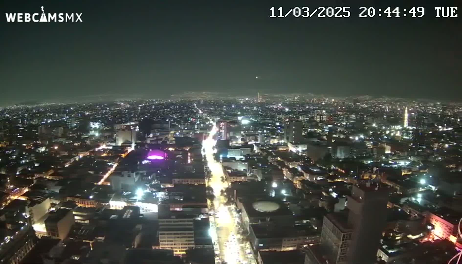 A nighttime aerial view of a brightly lit city under a clear sky.