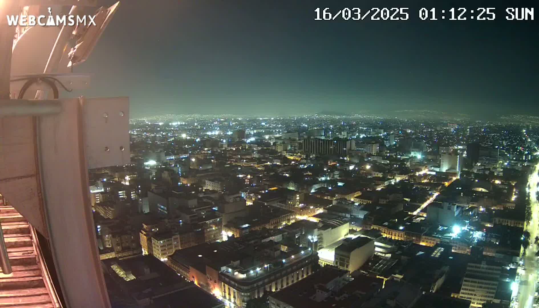 A nighttime, high-angle view of a sprawling city illuminated by numerous lights.