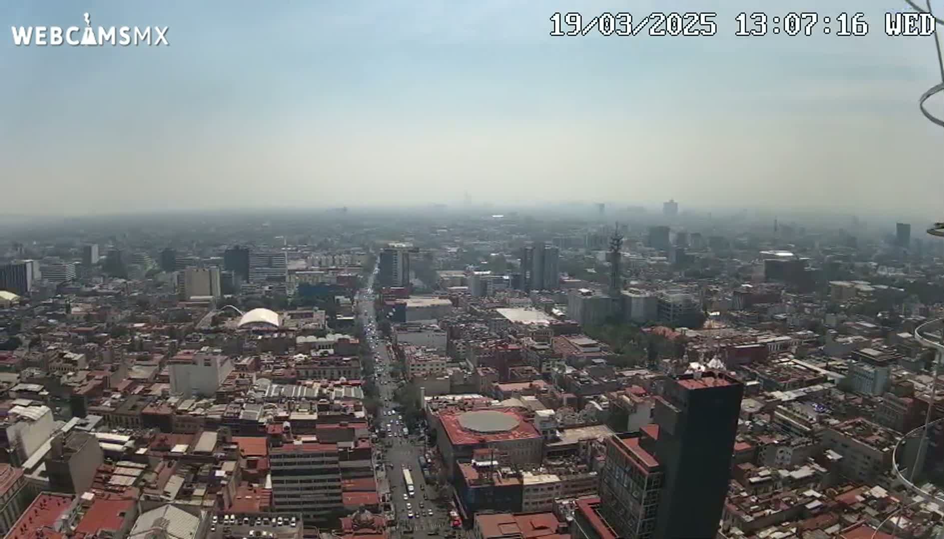 A hazy, high-angle view shows a sprawling city with numerous buildings and streets stretching to the horizon.