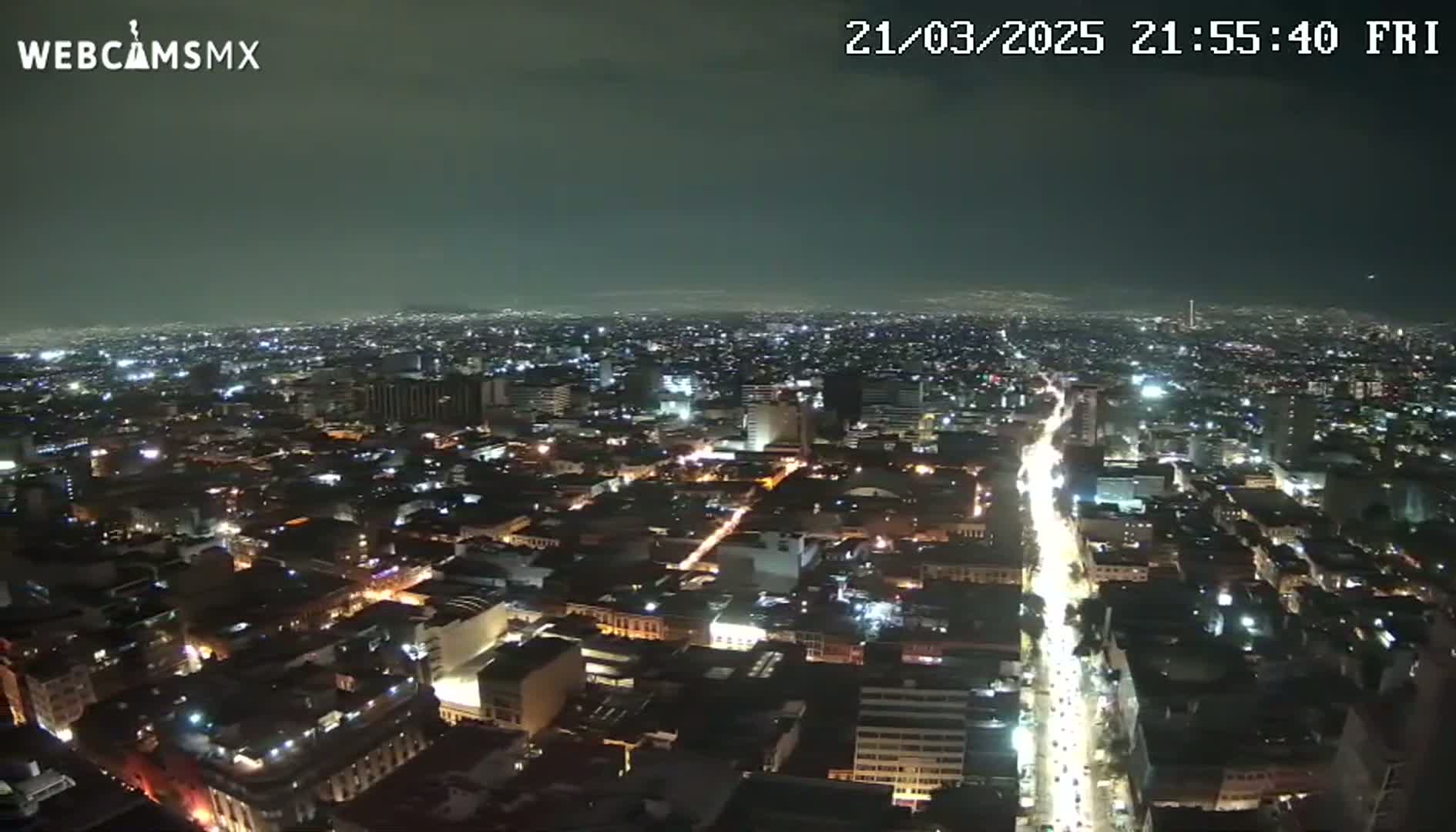 A nighttime aerial view of a sprawling city illuminated by streetlights and building lights under a clear, dark sky.
