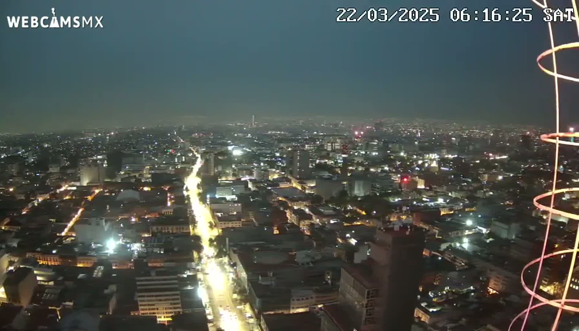 A nighttime aerial view of a city illuminated with streetlights under a dark, clear sky.
