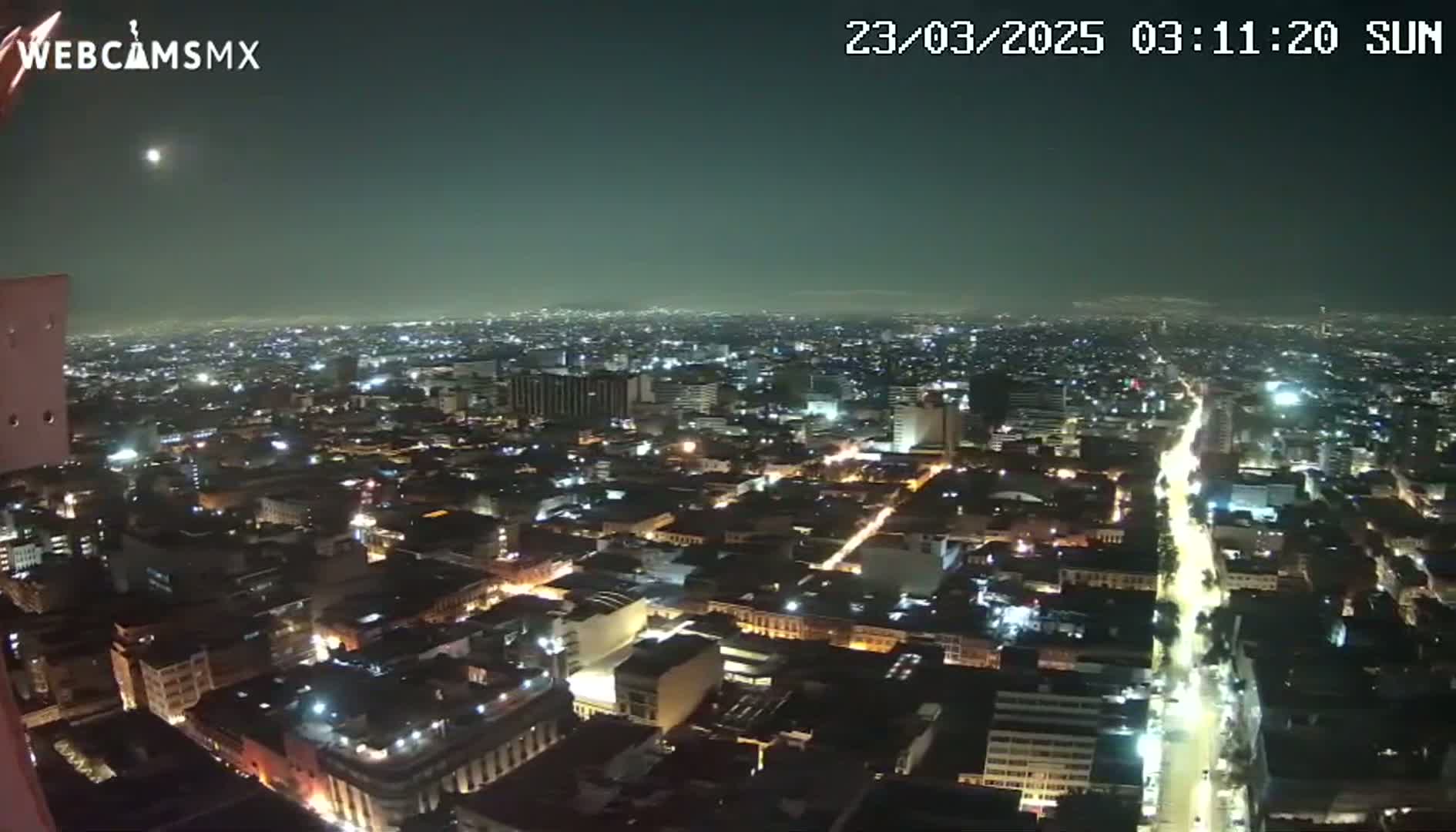 A nighttime, high-angle view of a sprawling city with illuminated streets and buildings under a clear, dark sky.