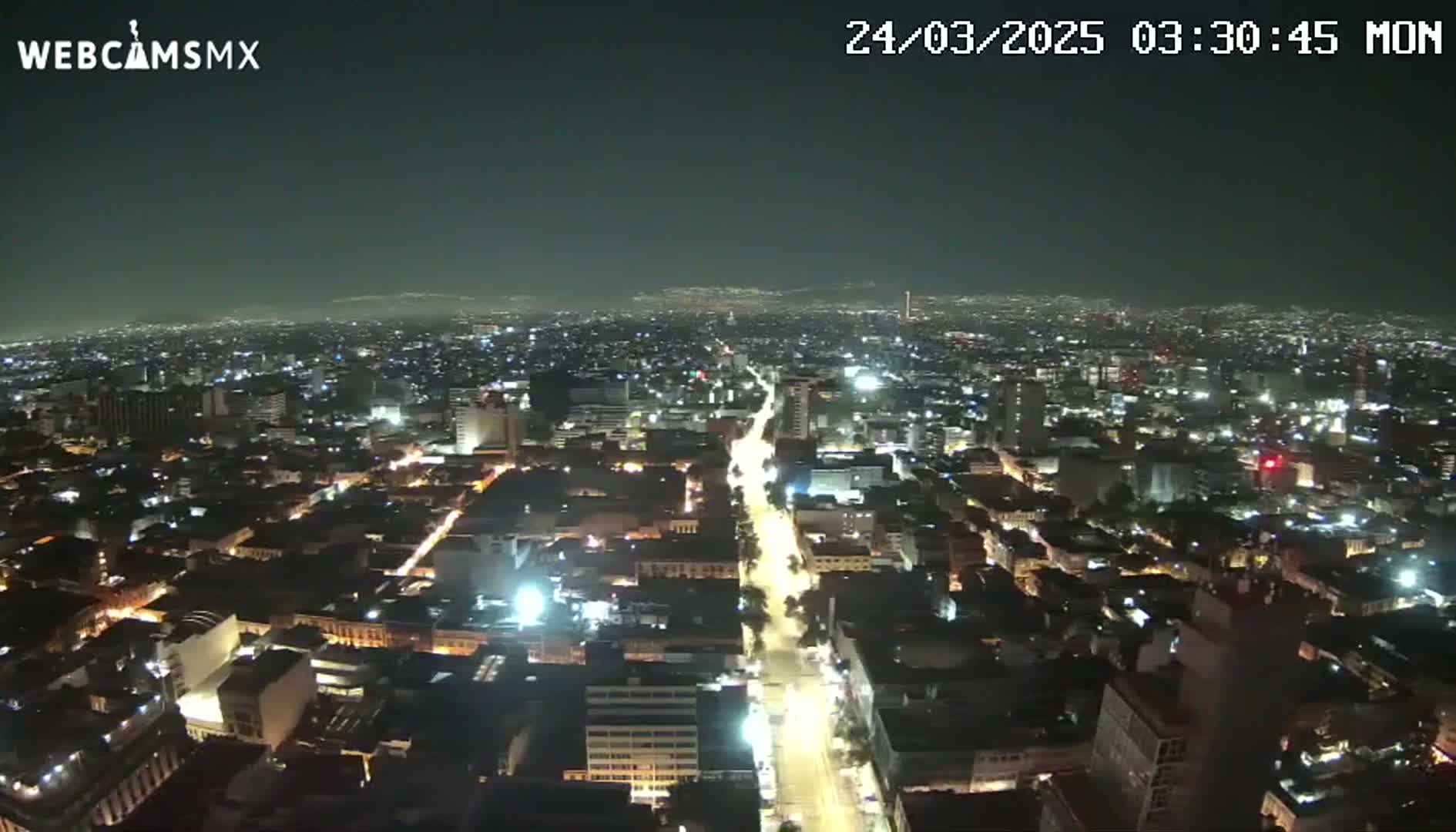 A nighttime, high-angle view of a sprawling city illuminated by streetlights and building lights.