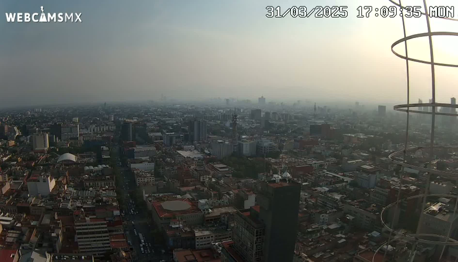 A hazy, high-angle view of a sprawling city, seen at dusk or dawn.