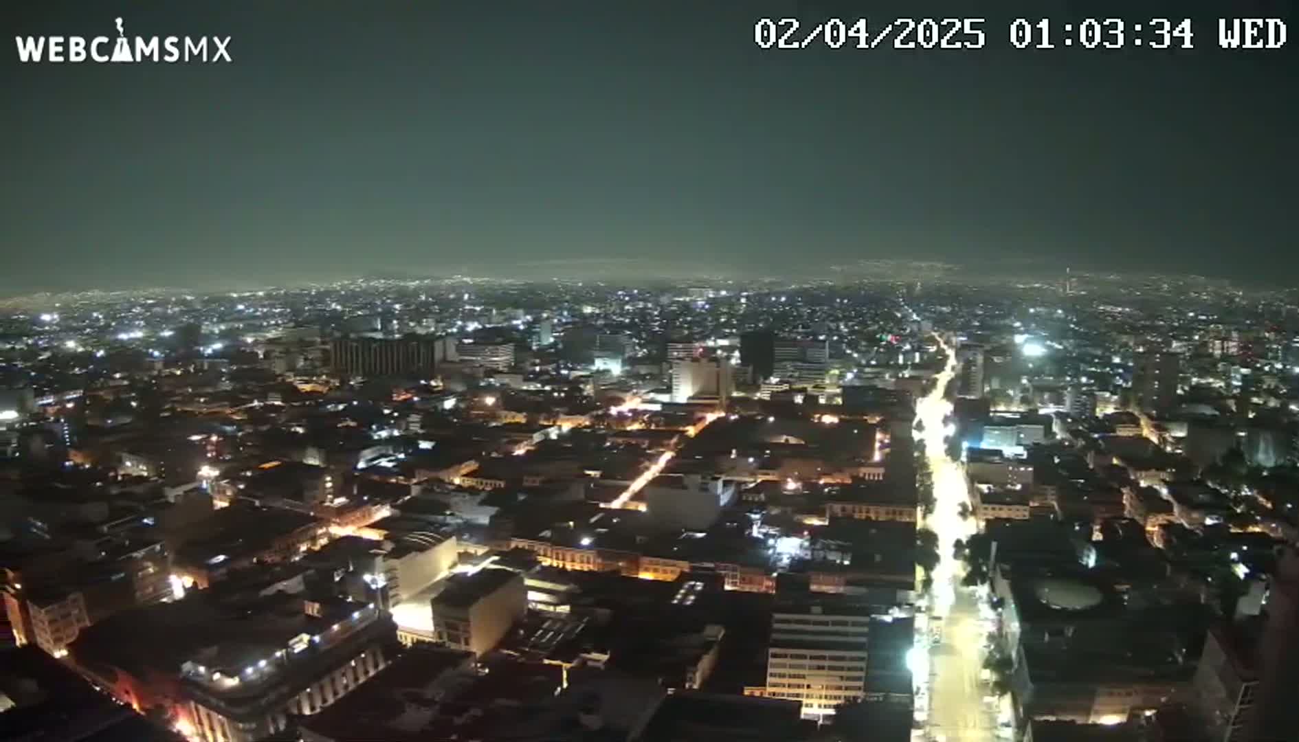 A nighttime aerial view of a city with a clear sky shows many buildings illuminated by streetlights and other lights.