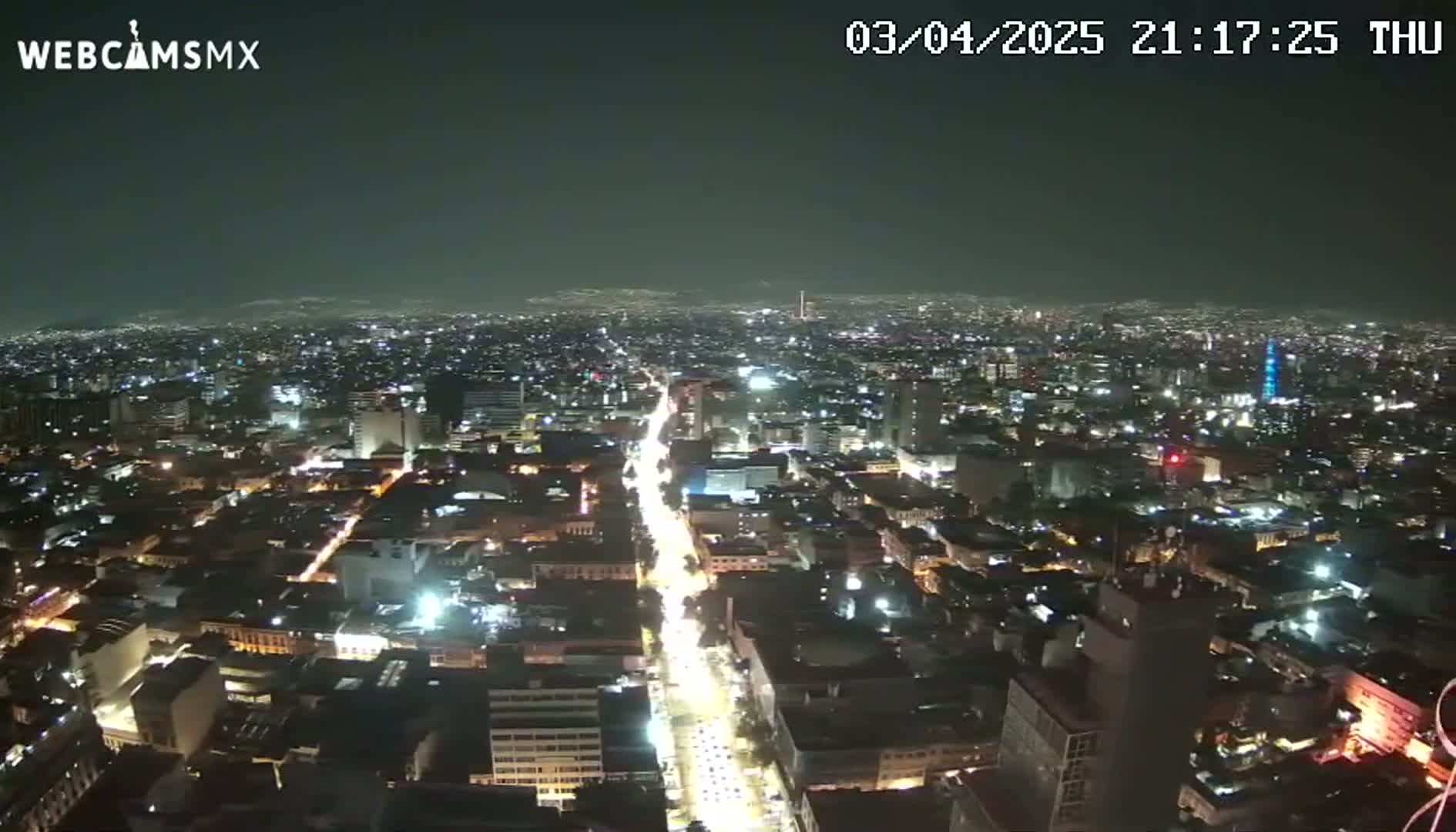 A nighttime aerial view of a sprawling city with brightly lit streets and buildings under a clear sky.