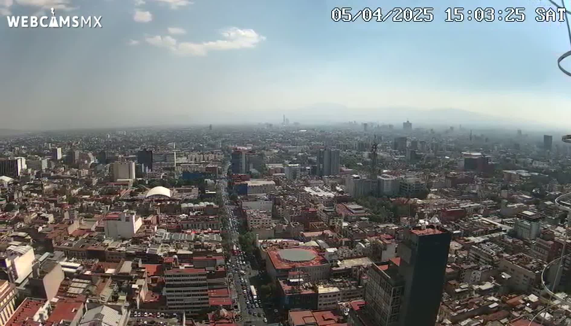 A hazy, sunny day reveals a sprawling cityscape, viewed from a high vantage point.