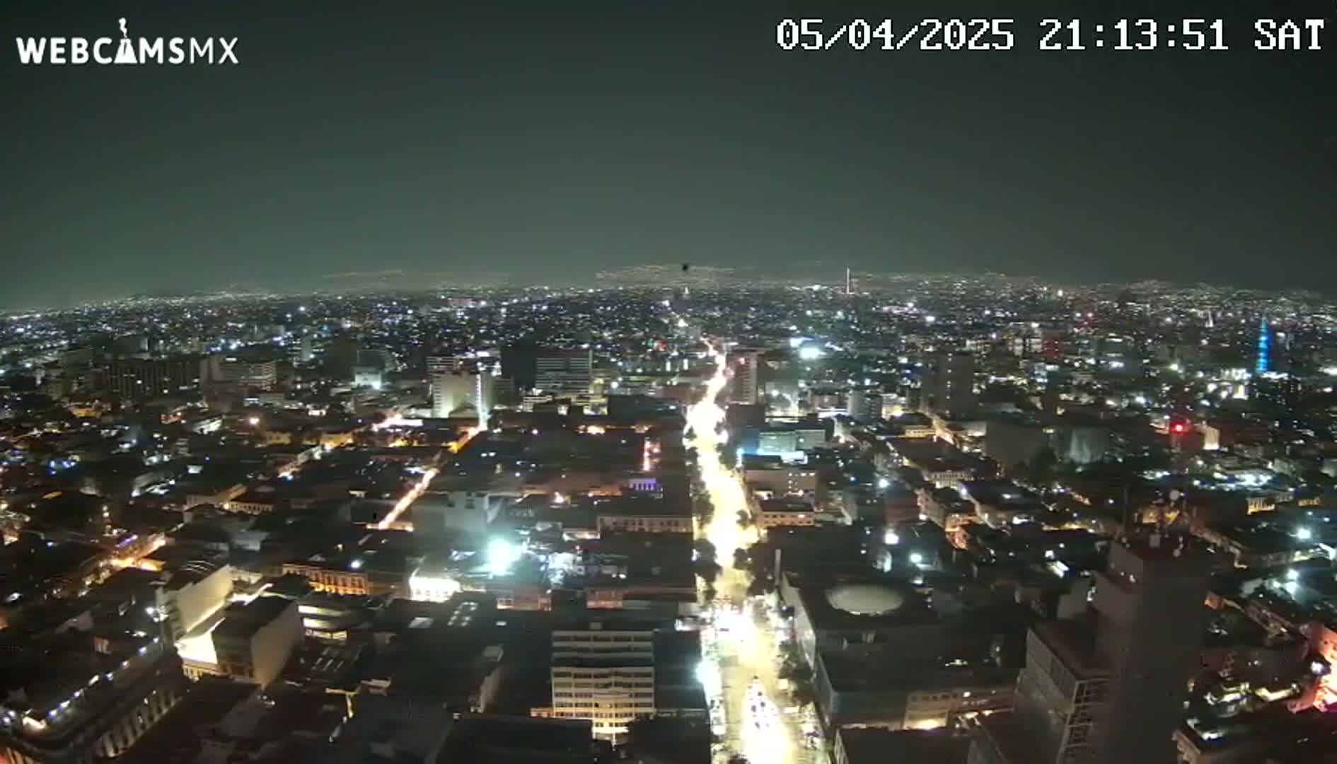 A nighttime, high-angle view of a sprawling city with illuminated streets and buildings under a clear, dark sky.