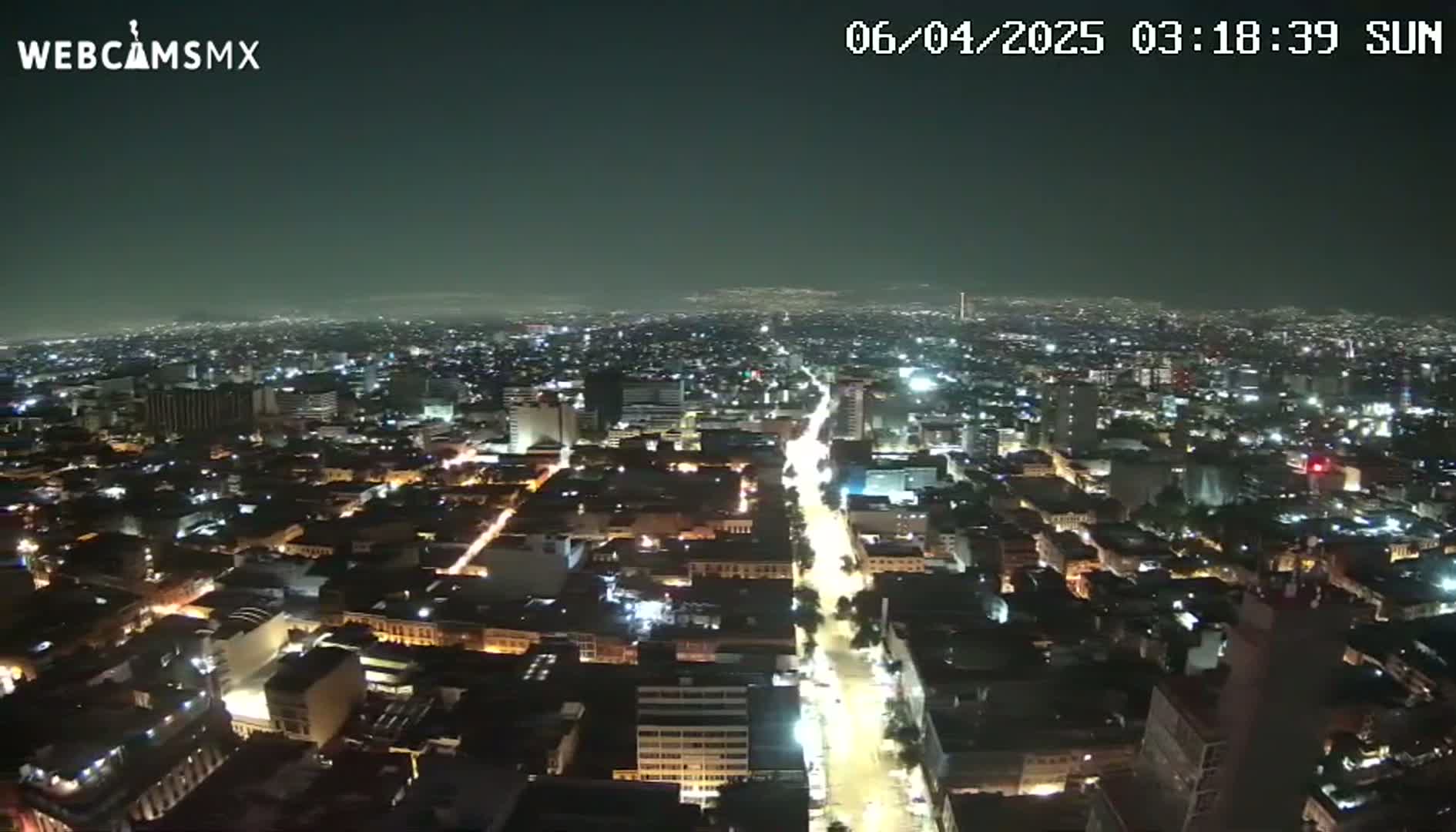 A nighttime, high-angle view of a sprawling city with illuminated streets and buildings.