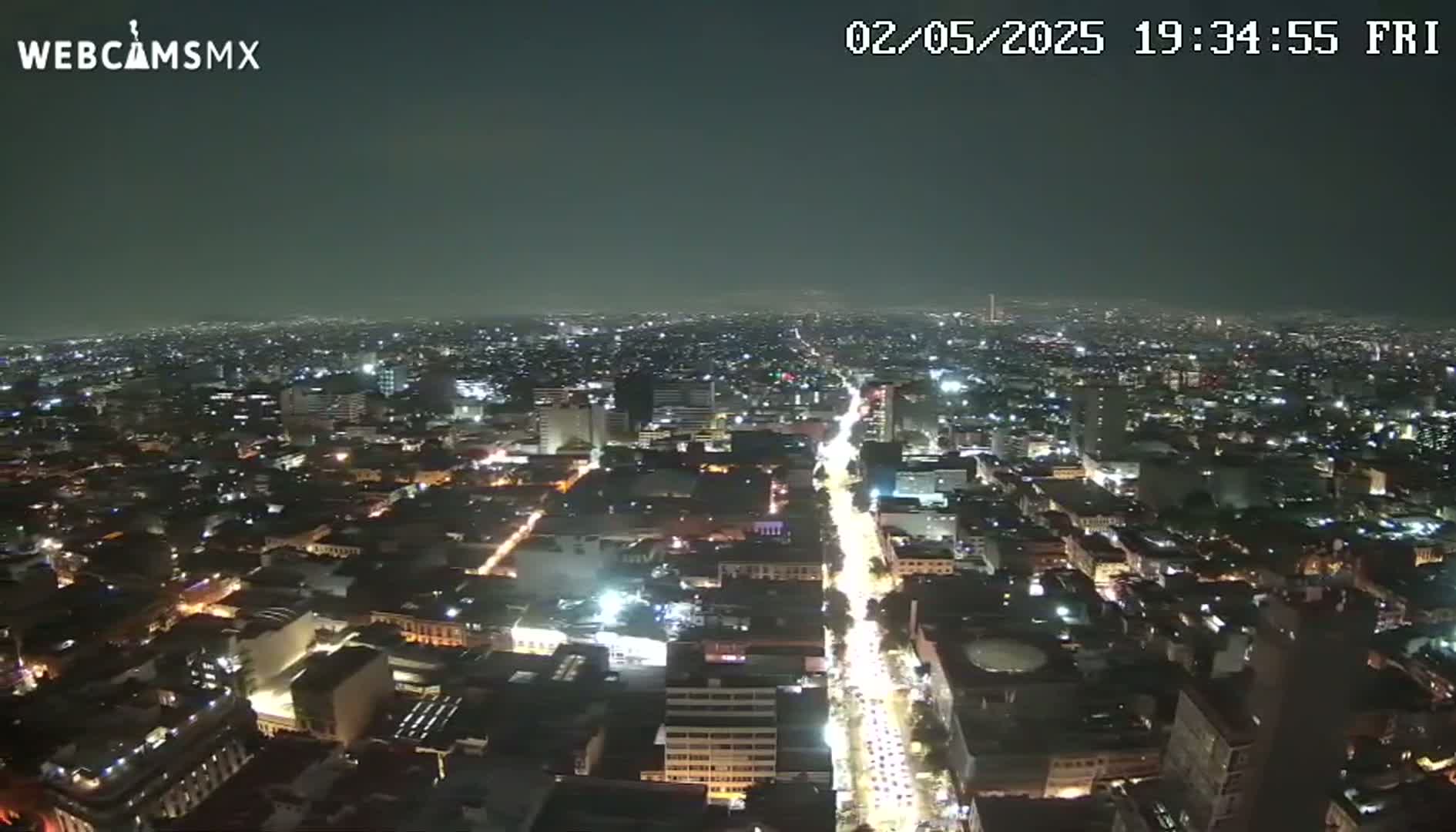 A nighttime aerial view of a sprawling city with brightly lit streets and buildings under a dark, clear sky.